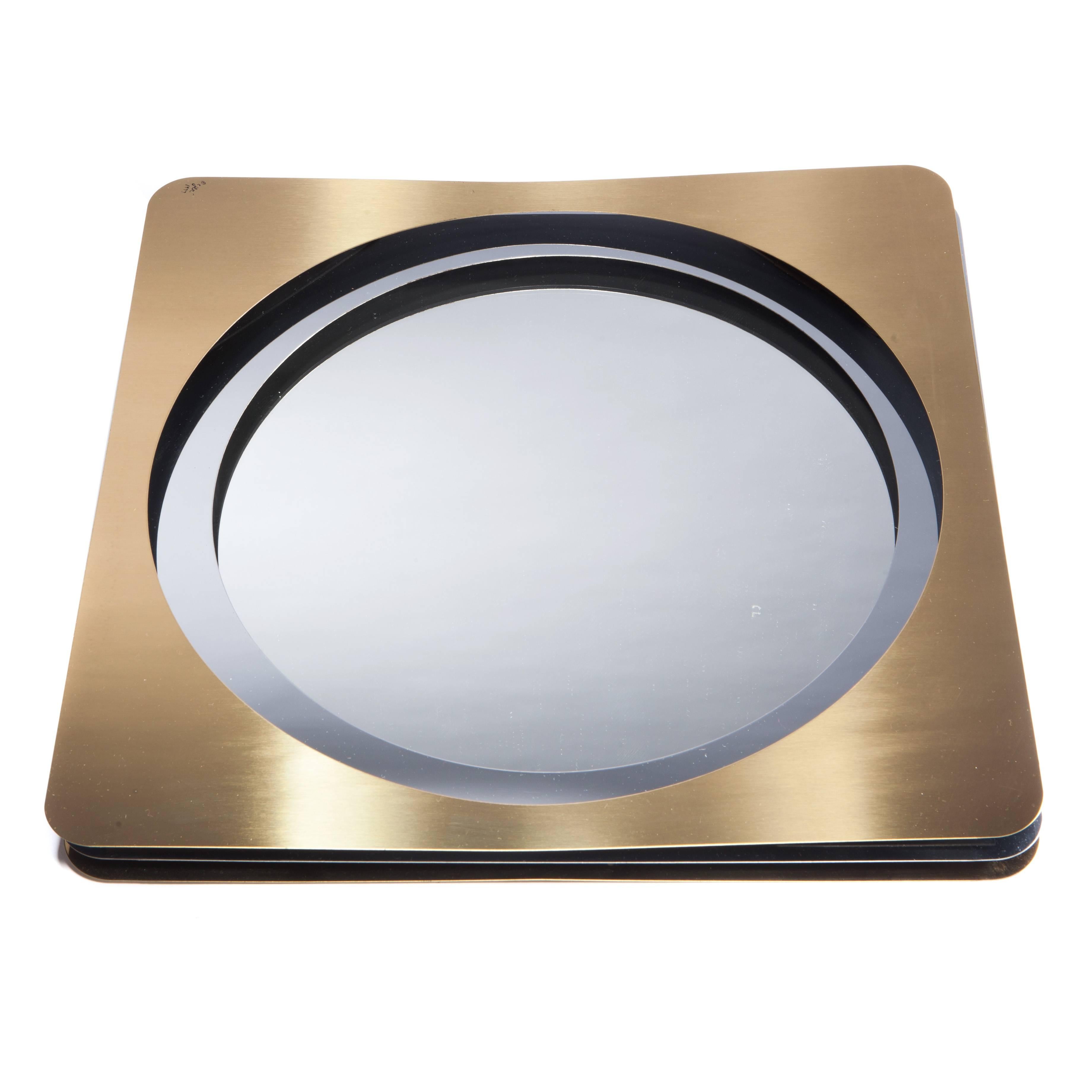 Layered panels in brass and chrome, with concentric circular cut-outs, lend depth to this three-dimensional mirror. Signed 