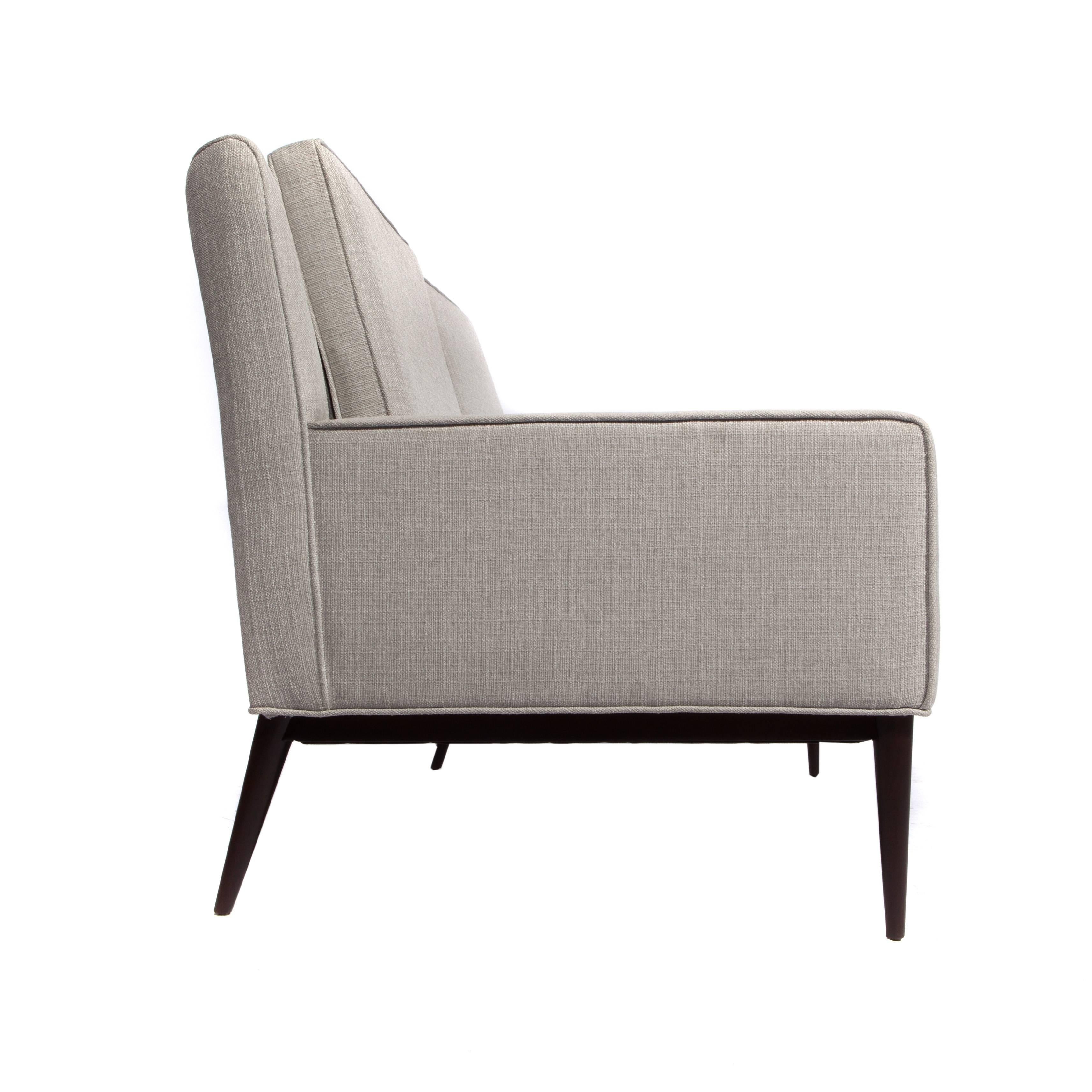 Chic, curved-back 1950s Paul McCobb loveseat floating on tapered and angled walnut legs. Newly restored and reupholstered in a light silver-gray woven fabric. Fabric swatch available. 




