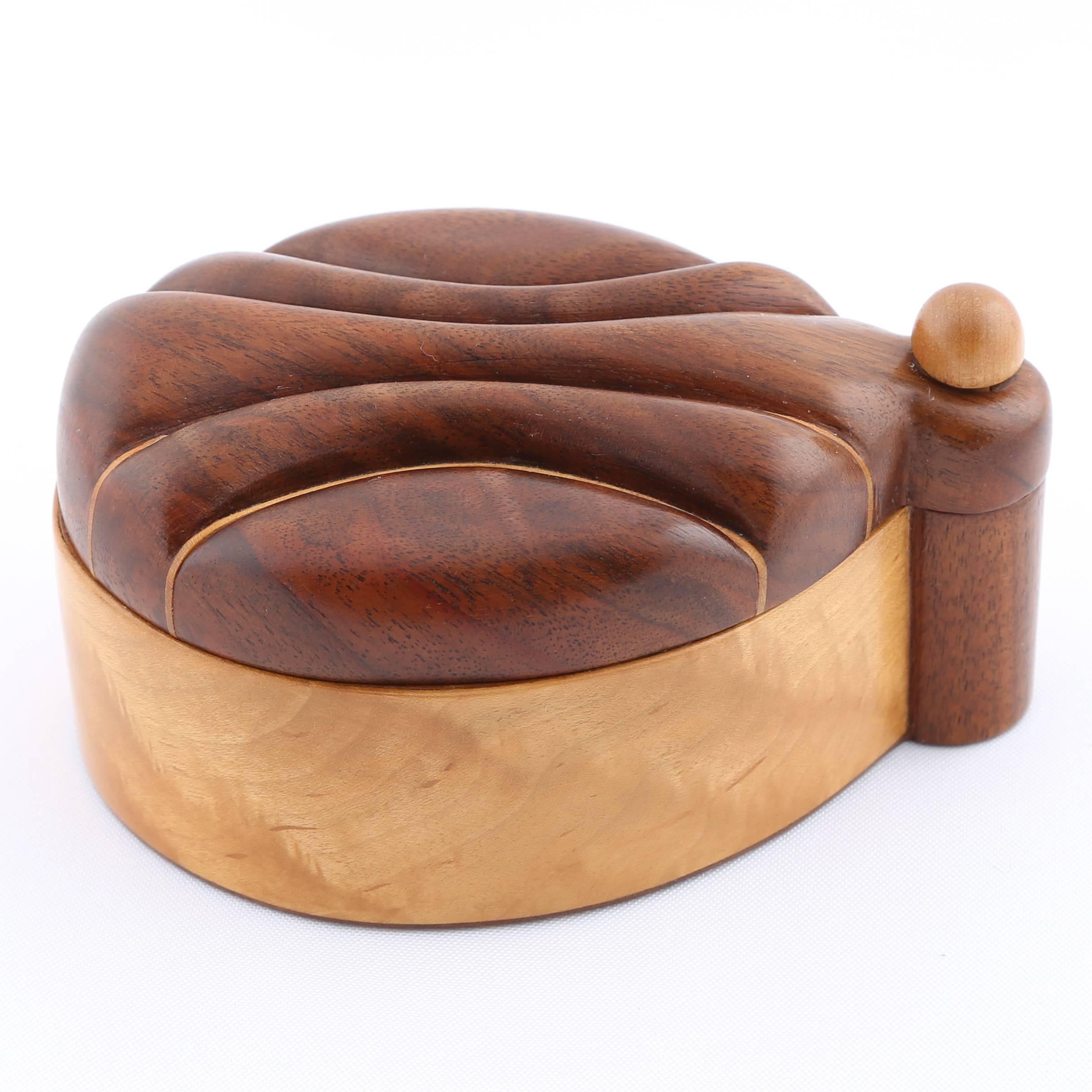 Lovely oval box with carved, swing-open top, made of mixed exotic woods and lined in black leather. Jerry Madrigale worked for Knoll's design and development division for many years and was in charge of prototyping anything made of wood or with
