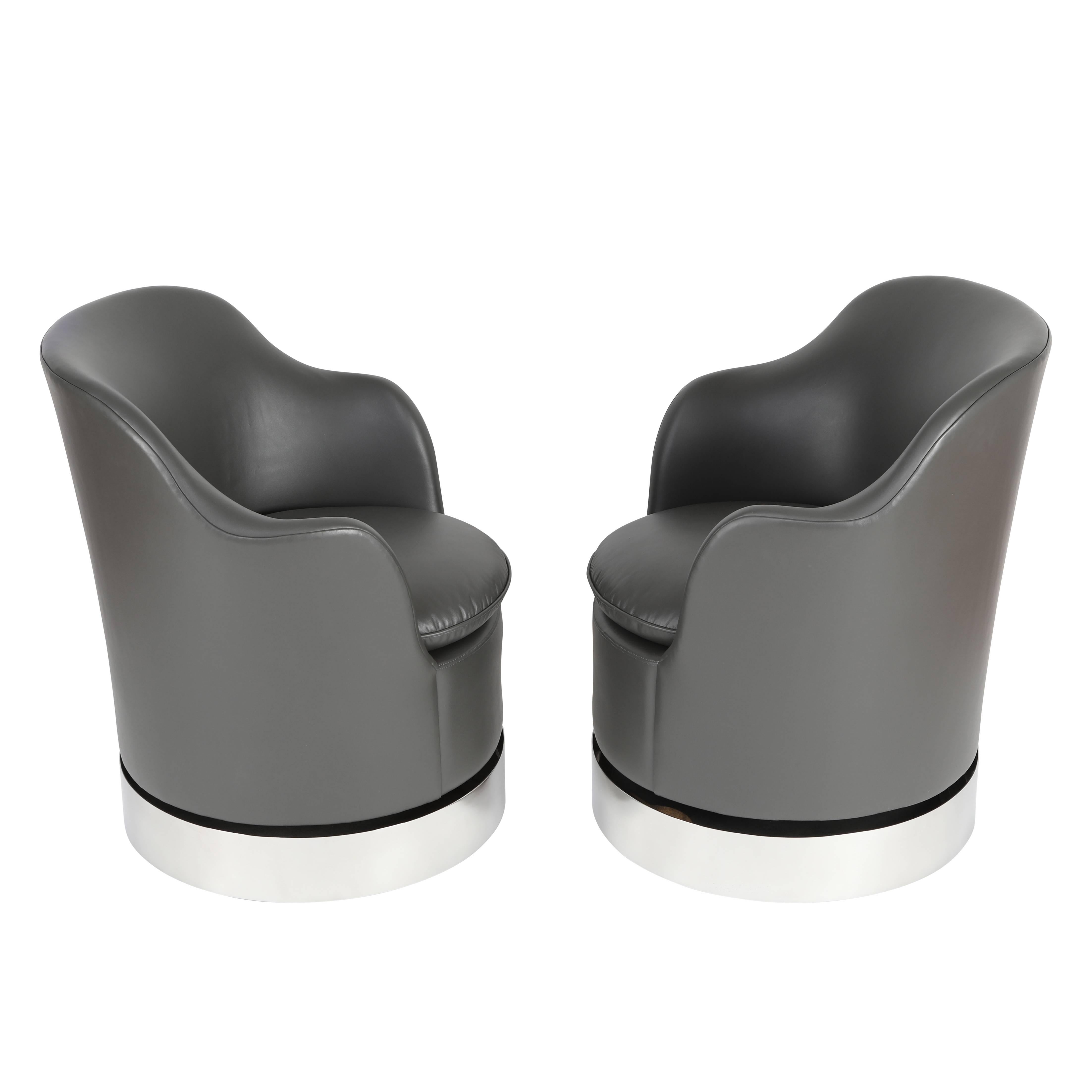 This beautifully crafted pair of tilt and swivel chairs features a circular-form body with curved backrest sloping down to integrated arms. Each chair features a single, reversible seat cushion. The conforming base is a seamless piece of highly