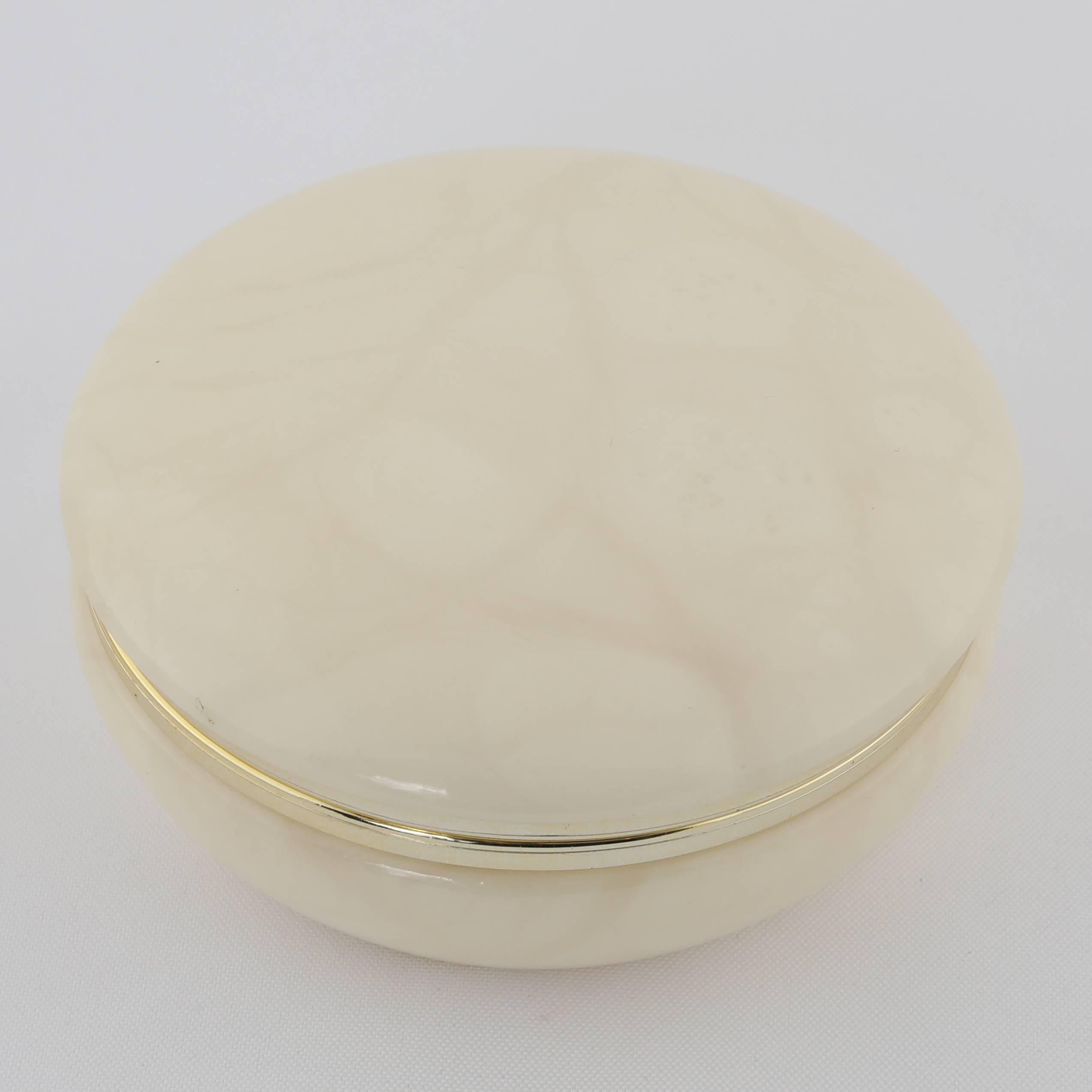 Circular, hand-carved box in a warm, creamy polished alabaster. Shiny brass trim on upper and lower edges. Hinged lid. 
