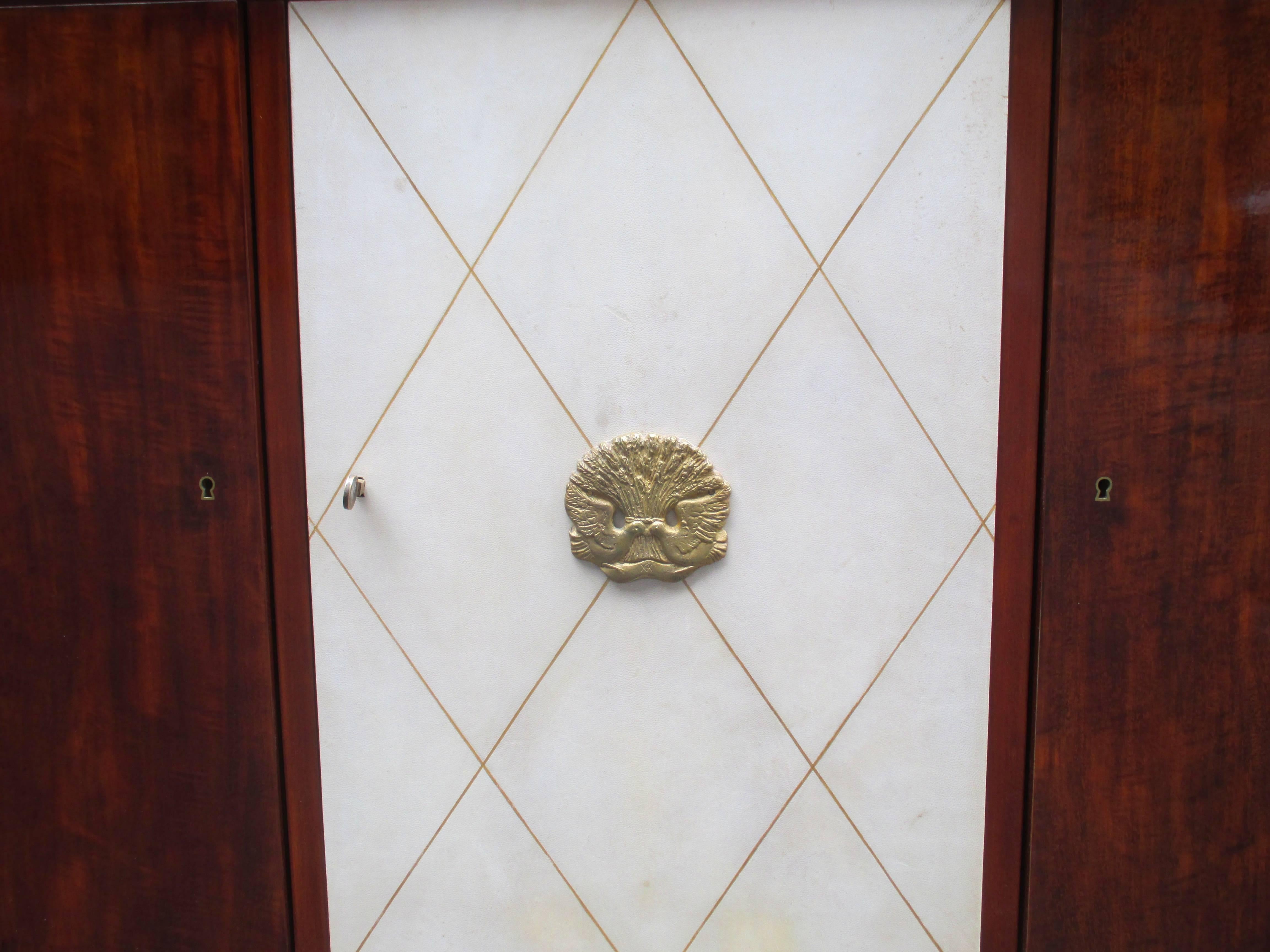 A modernist three-door sideboard
by André Arbus with bronze work by Vadim Androusov.
Mahogany with a parchment covered 
center door detailed with gold tooling.
Patinated bronze details and central bronze ornament.