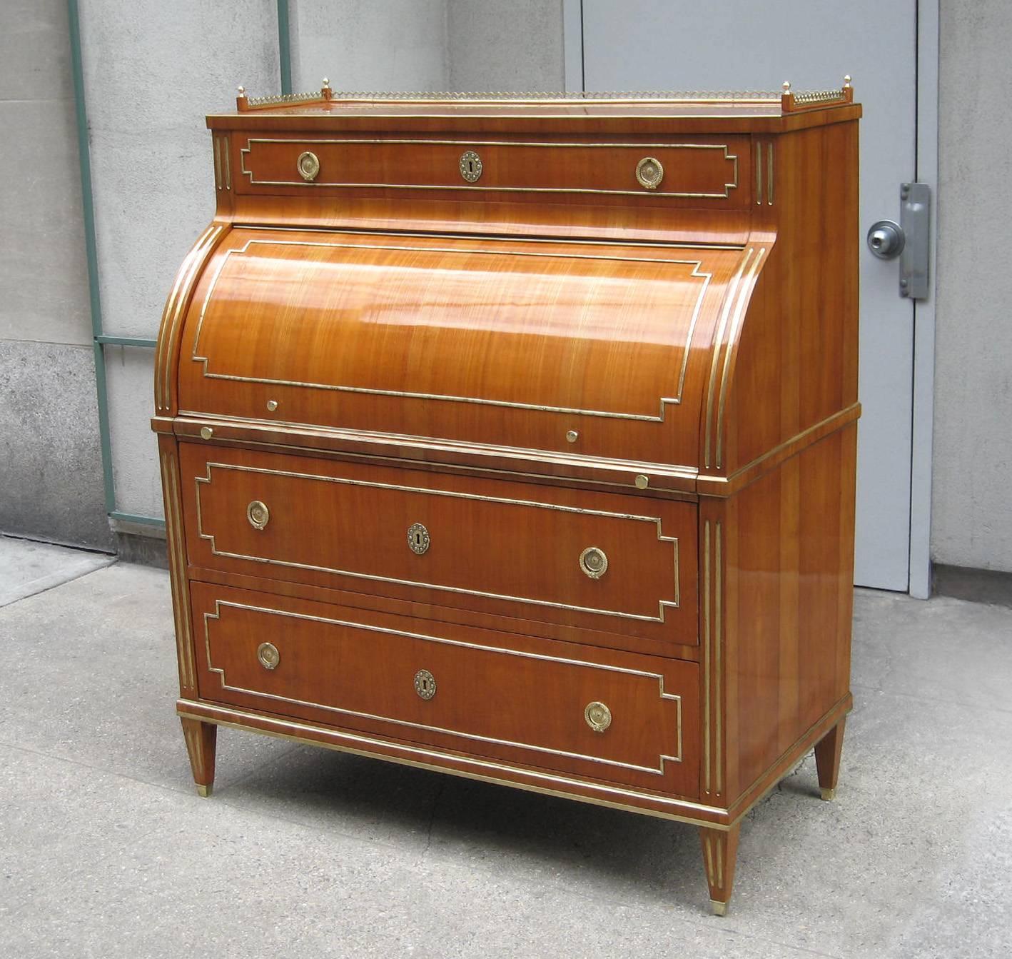 A fine Neoclassical roll-top desk or secretary.
Cherrywood with patinated brass details, pulls, 
escutcheons and sabots. With three drawers and 
four additional smaller drawers inside the roll top.
The writing surface with leather inset can be