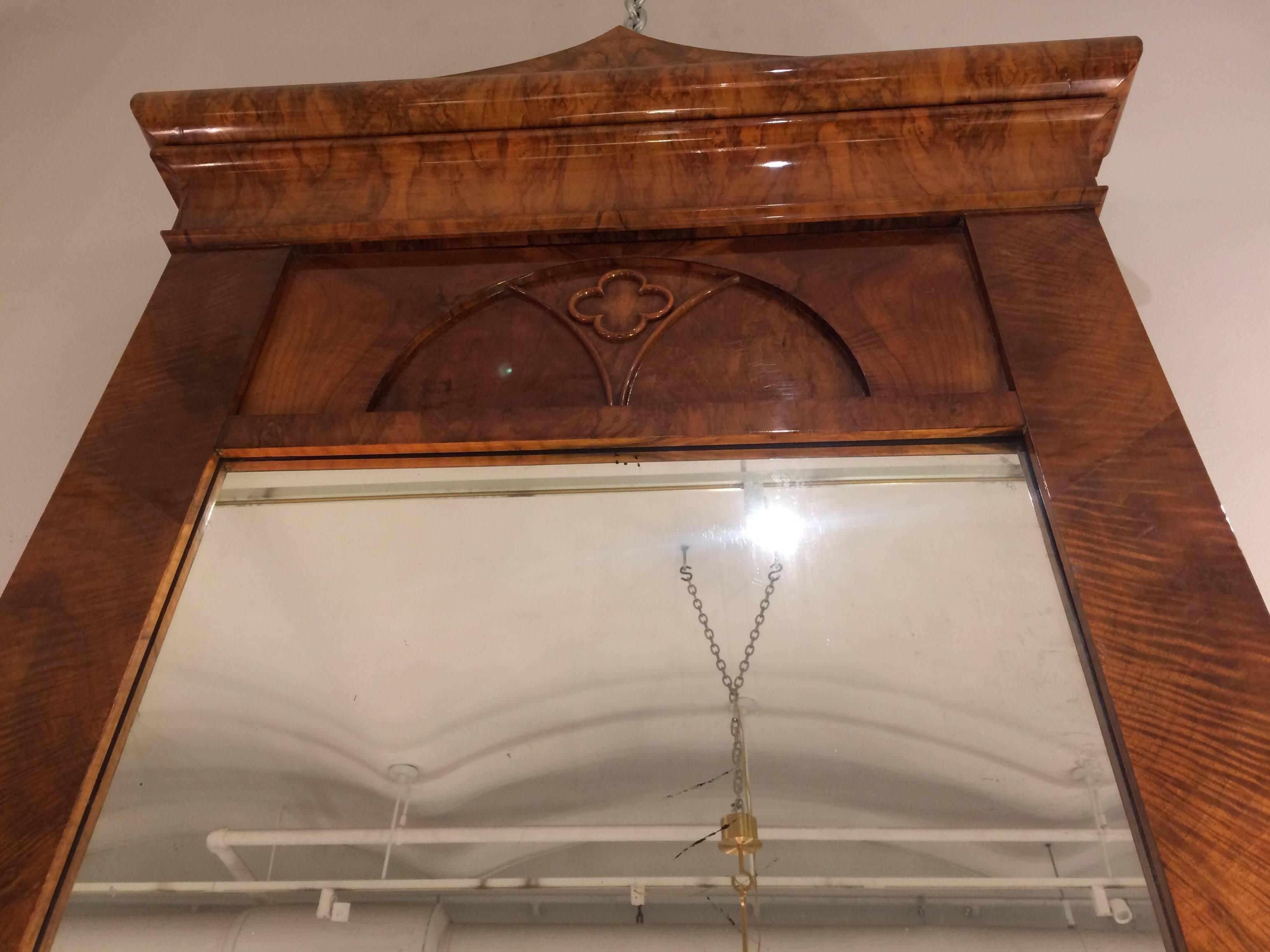 An outstanding Biedermeier period walnut mirror of impressive scale from Austria circa 1820. The unique pagoda shaped crown surmounts an interior arch enclosing a raised four lobe medallion. Constructed of highly figured burl walnut with Inlay work