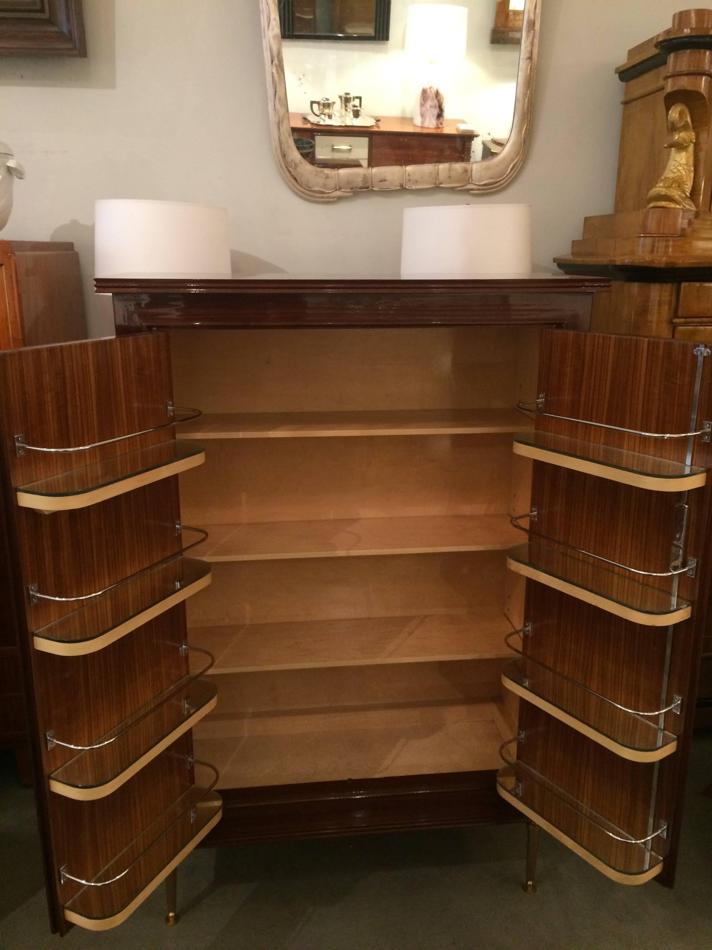 A fine Jules Leleu designed modernist two-door bar cabinet.
Mahogany marquetry details on the doors,
resting on patinated gilt bronze legs. Interior door shelves 
crafted in polished nickel with mirrored bottoms.

Complete professional restoration