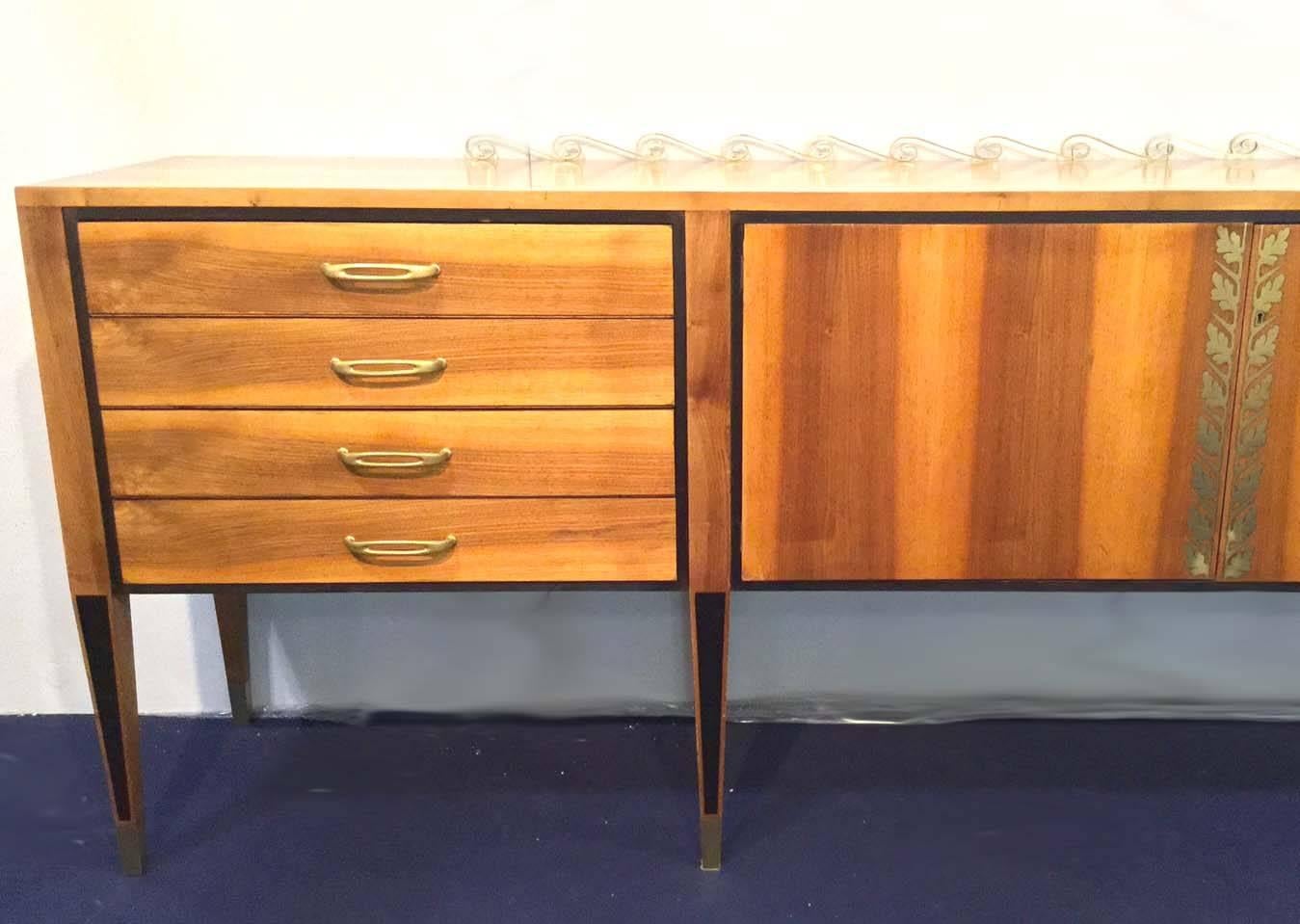 Magnificent solid walnut sideboard with two central doors and drawers, it has rich brass decoration on the top and in the central board of the doors, also the handles are in brass on the drawers and the final feet, ebonized bands and profiles are