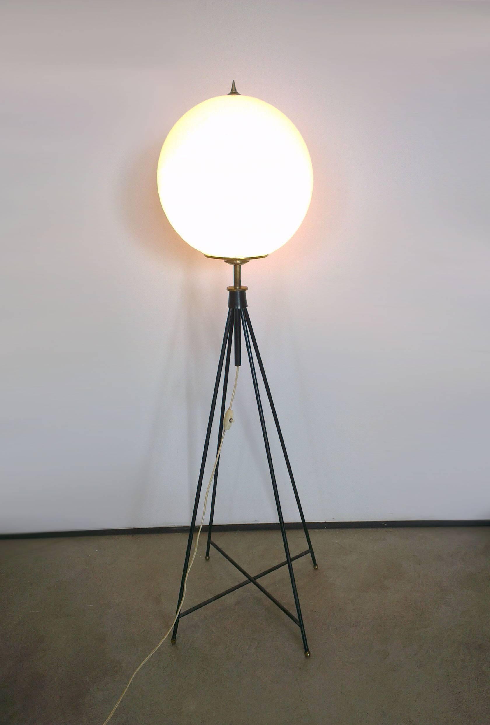 Elegant floor lamp by Stilnovo, 1950.
Four black lacquered brass stems are linked at the base by a crossbeam and are surmounted by a large opaline glass ball as diffuser.
The wire system is outside the structure and its functioning.
Made by