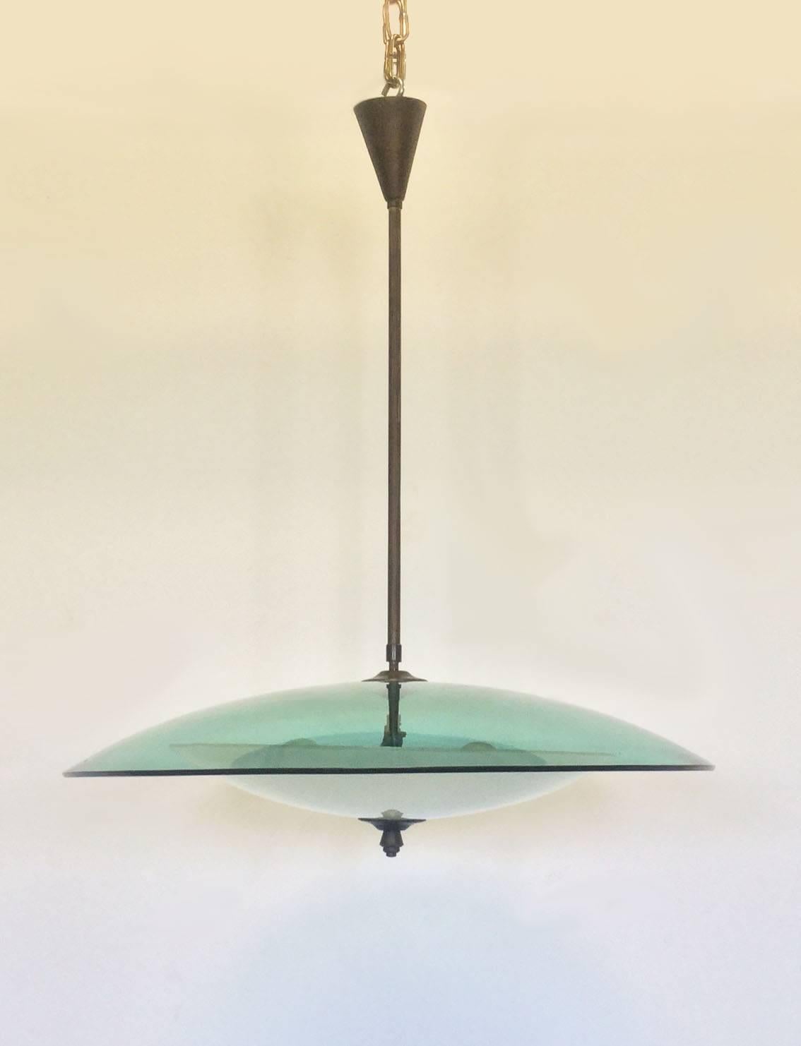 Elegant chandelier with white opaline cup as diffuser surmounted by a large green glass curved cup, brass stem that ends with brass screw pyramid.
Functioning wire system, 
Fontana Arte. 1950.