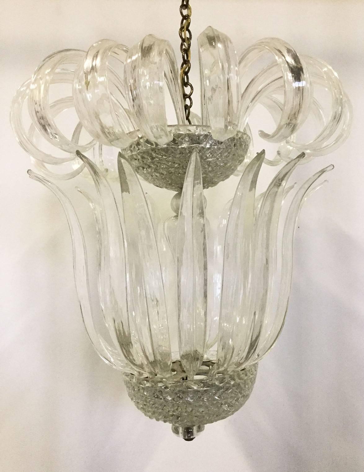 Classic and elegant chandelier, blown glass leaves grafted on beveled glass cups which hide the lights, glass stem with electric wire inside.
Original in all parts this model is made by Venini in 1940.