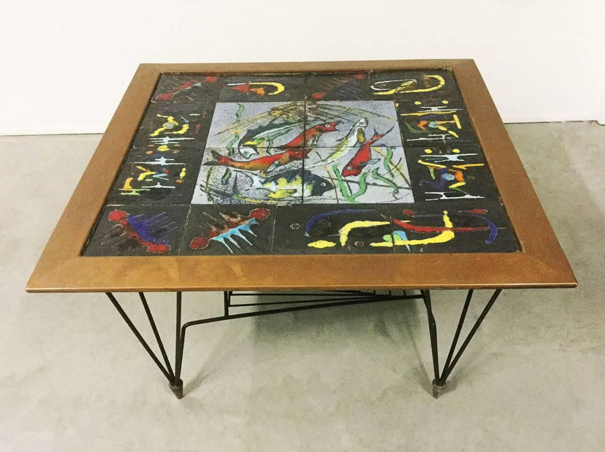 Coffee table with exceptional design and materials.
Black lacquered iron base with brass final feet, top made by ceramics tiles surmounted by a copper frame, the ceramics are enameled with abstract subjects and stylized drawing fish.
Very strong