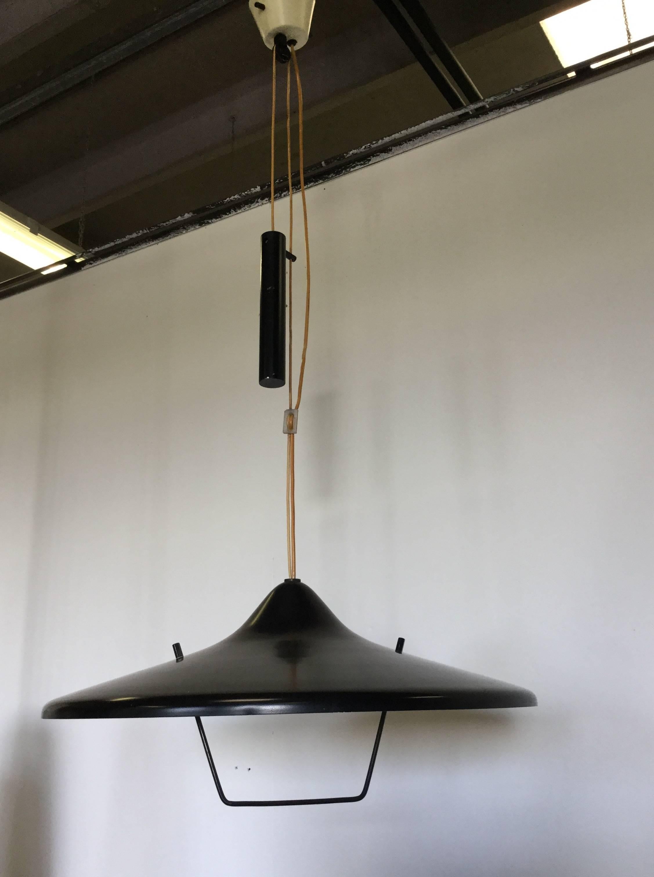Chandelier with pulley and counterweight that permit the adjustable movement up and down, the diffuser is a large black lacquered metal cup with its own hand to move, yellow Stilnovo label under the cup 
Manufactured by Stilnovo in 1950.
