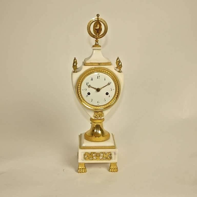 Louis XVI white marble and gilt bronze marble clock, the white enamel dial with Arabic numerals within a lyra-shaped marble case surmounted by pine finials and centred by an armillary dial, raised on a circular stem above a stepped square marble