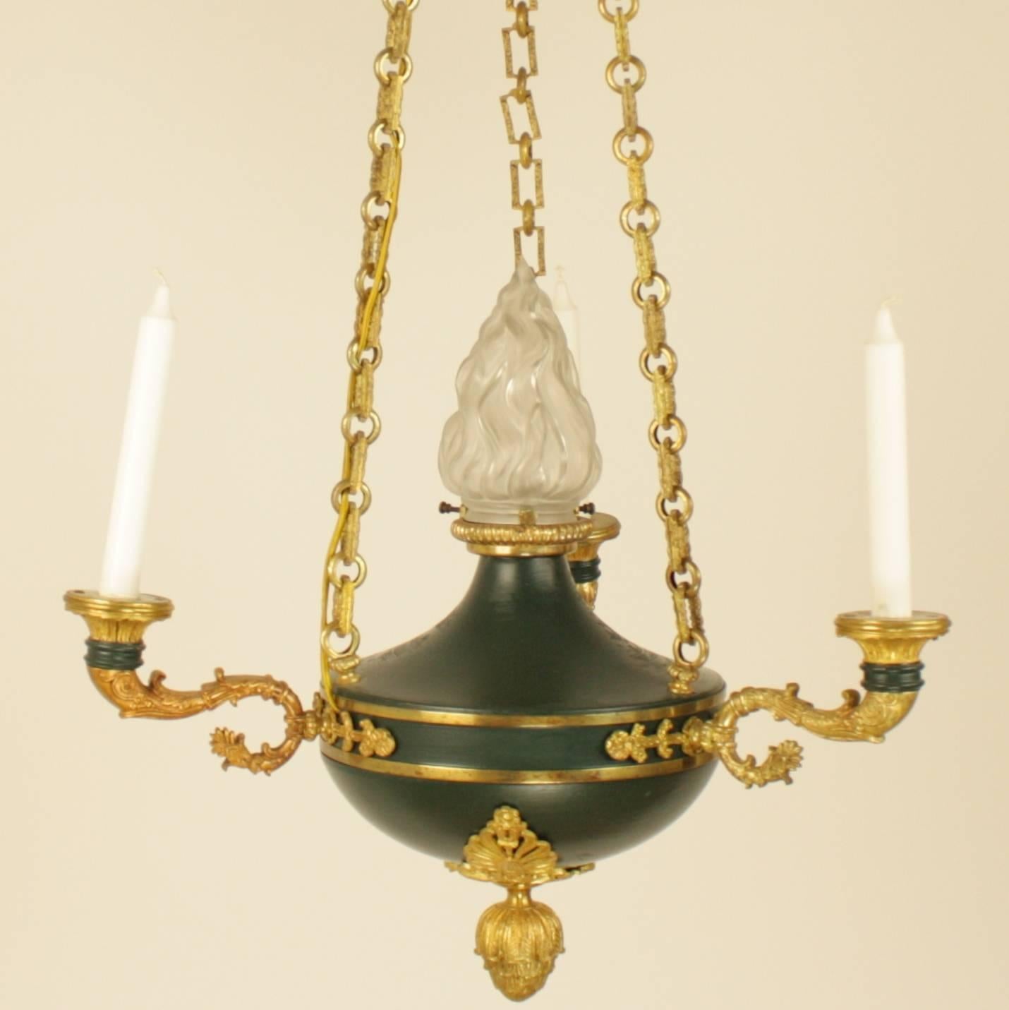 Empire style gilt bronze and green tole three-light candelier, the circular corona decorated with palmettes above the acanthus leave finial, the link chains connecting to the green painted tole font, supporting three foliate scrolled candle branches