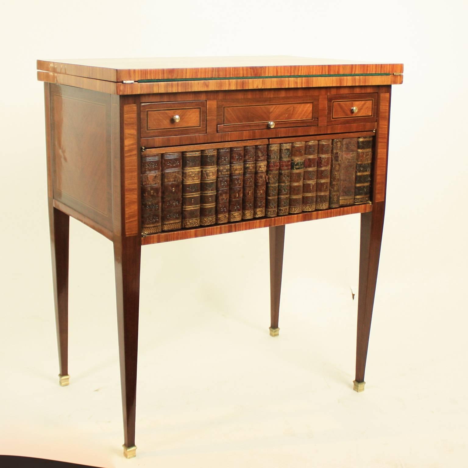 A 19th century French game table with chess board marquetry on top unfolding to double the size revealing a green felt covering. The frieze with two drawers and a centered pull-out slide above a two doors featuring the spines of vintage leather