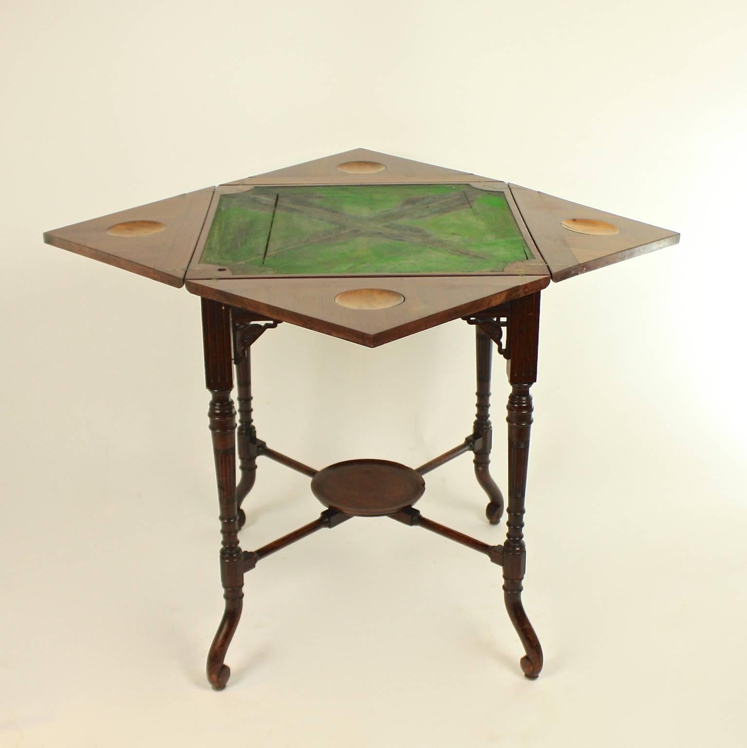 An Edwardian envelope card table which opens to reveal baize playing surface with four money wells in satinwood, above a single frieze drawer, raised on elegantly turned legs with a lower center tier platform.
This wonderful card table is in