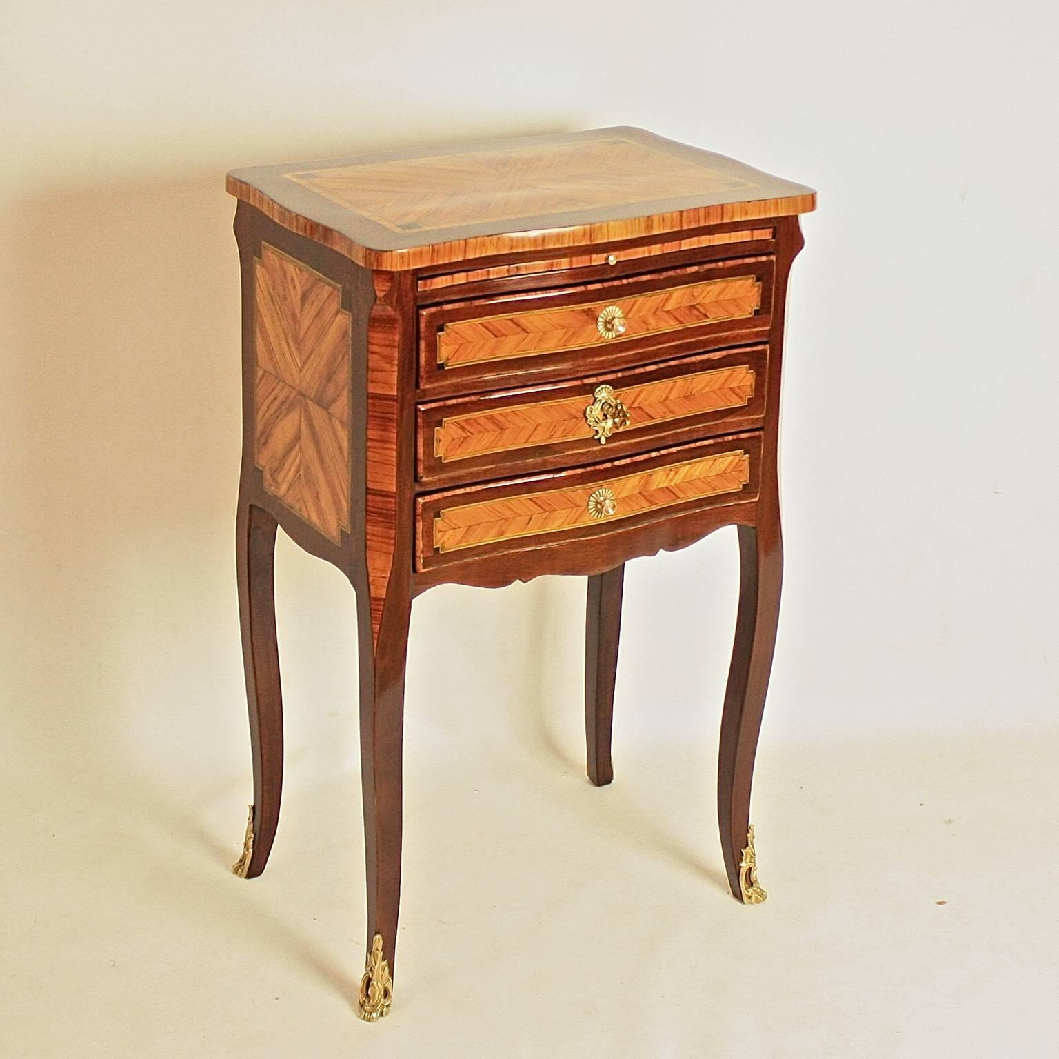 A Louis XV gilt bronze mounted kingwood and amaranth marquetry center table, a so called 'table chiffonière', with a marquetry shaped top above three serpentine drawers, with a shaped apron and canted corners, on slender cabriole legs with gilt