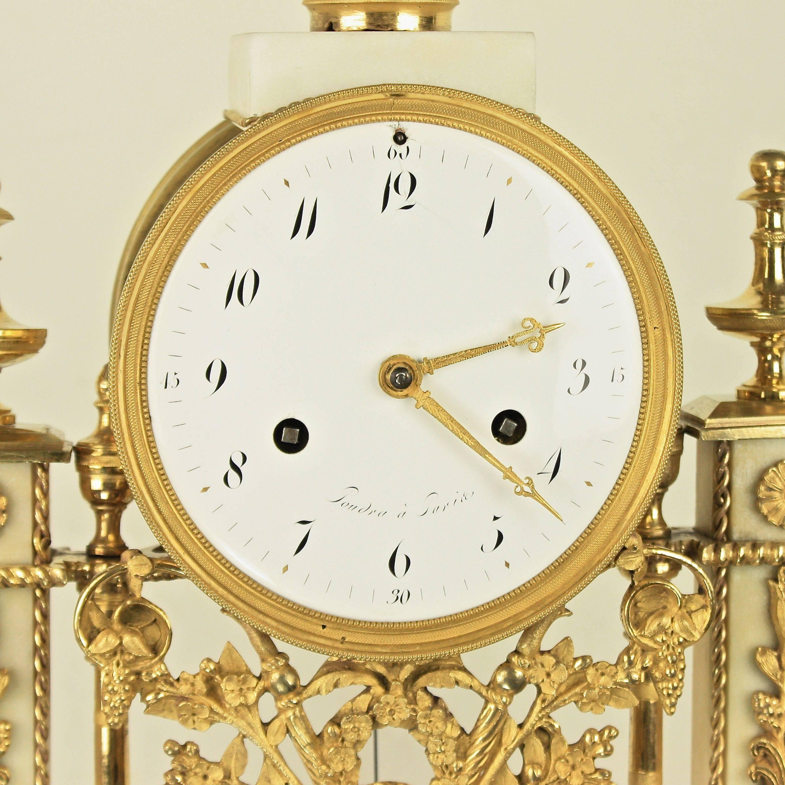 Late 18th century Carrara and black marble ormolu mantel clock, the white enamel dial with Arabic numerals signed „Poudra à Paris“, surmounted by a marble vase overflowing with finely chased ormolu flowers, berries and leaves. The angular columns