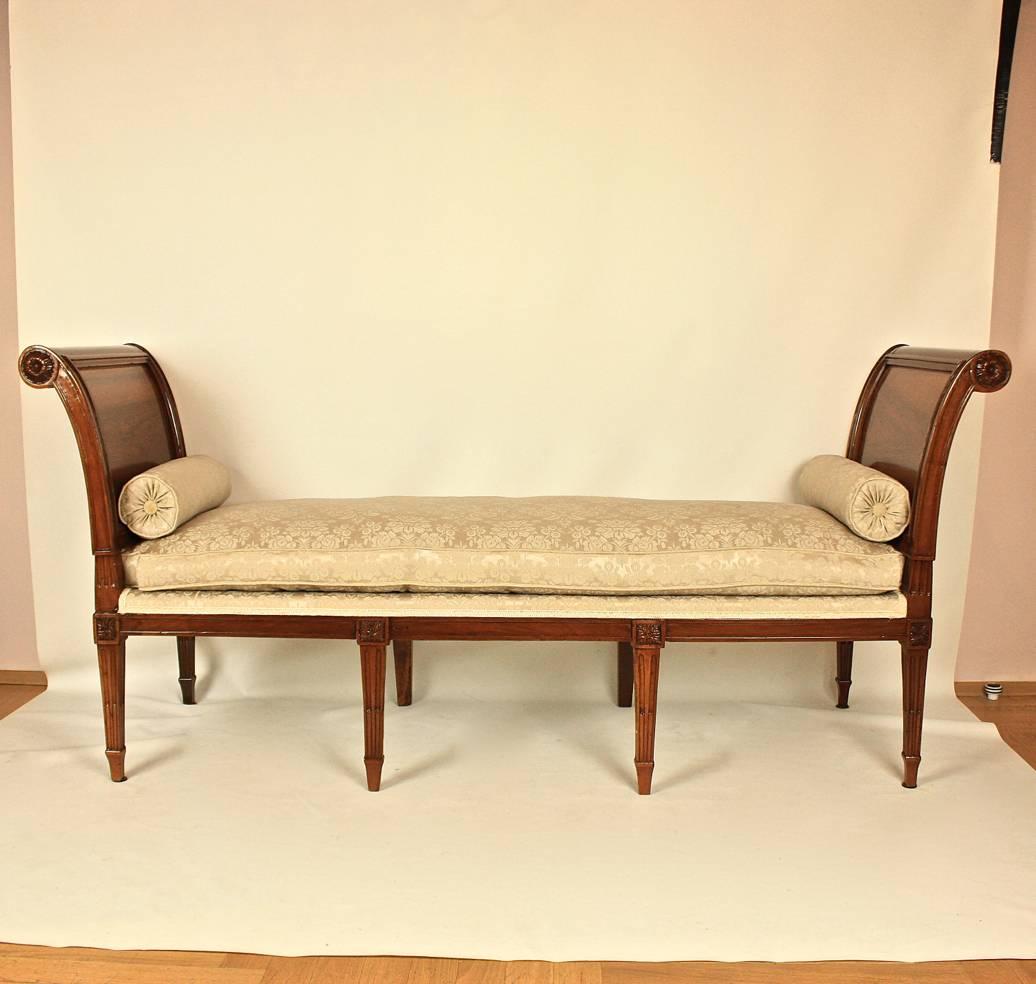 A late 18th century Louis XVI daybed or 'lit de repos', in the manner of Georges Jacob (1739-1814). Constructed in walnut with the swept ends of scrolled form, carved with flower heads and displaying the beautifully figured walnut, on eight