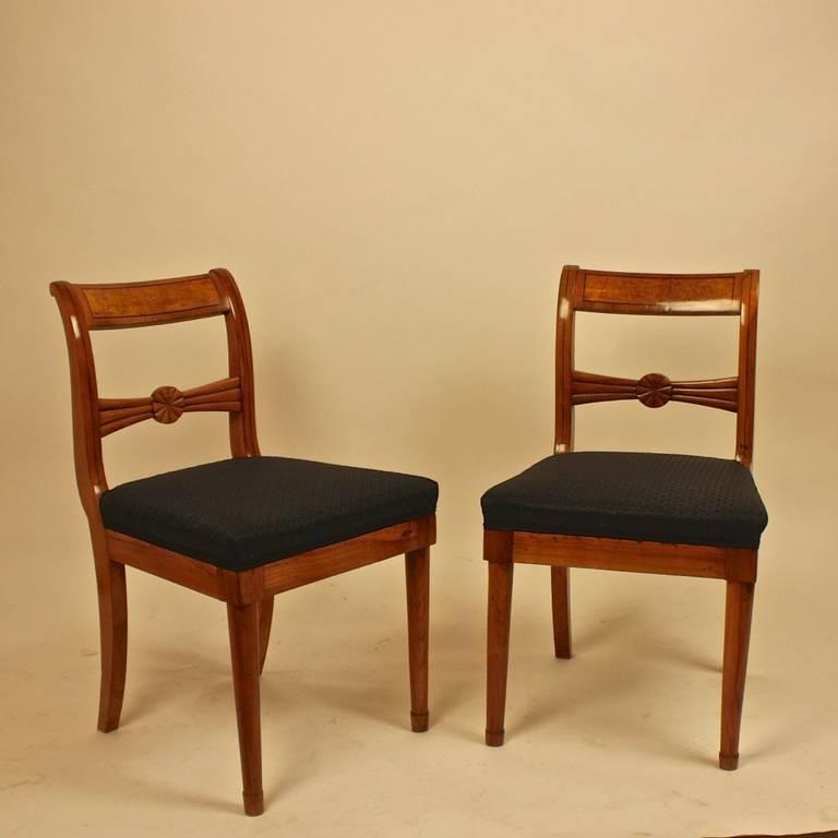 A pair of beautifully honey colored fruitwood Biedermeier side chairs, with gently curved rectangular backs, the top and side inlaid with banding, the splat carved with a stylized flower head, on sabre legs. Newly upholstered in black Prussian horse