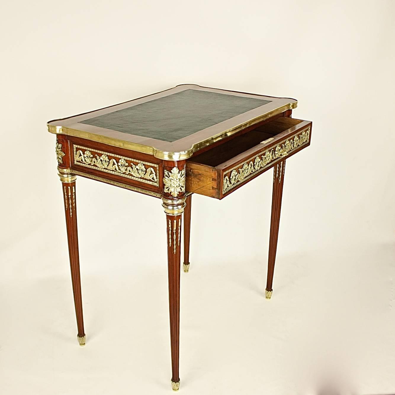 A rare and small 19th century, Louis XVI style bureau plat veneered in burr mahogany on an oak carcase set with brass mounts. The writing top covered with a green leather surface, the top accentuated by projecting round forecorners and further