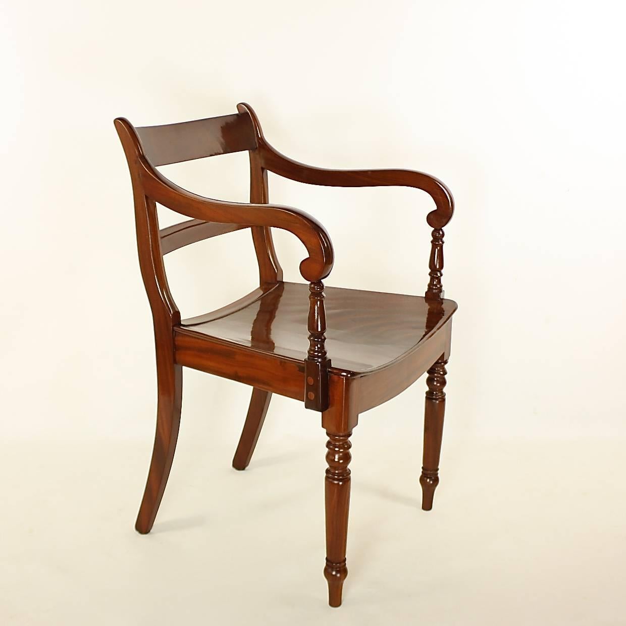 A pair of English Regency mahogany armchairs, the curved backs with top rails and horizontal splats below, with scroll arms on front ring-turned tapered legs and sabre back legs. The seats not upholstered but shaped for seating. The pair in