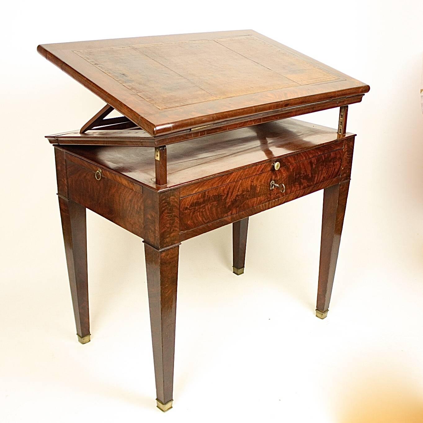 A late 18th century Directoire mahogany architect's table. A mechanical table with a double-hinged ratcheted top and the original gold-tooled brown leather lined writing surface, veneered in beautifully flame-grained polished mahogany. The long