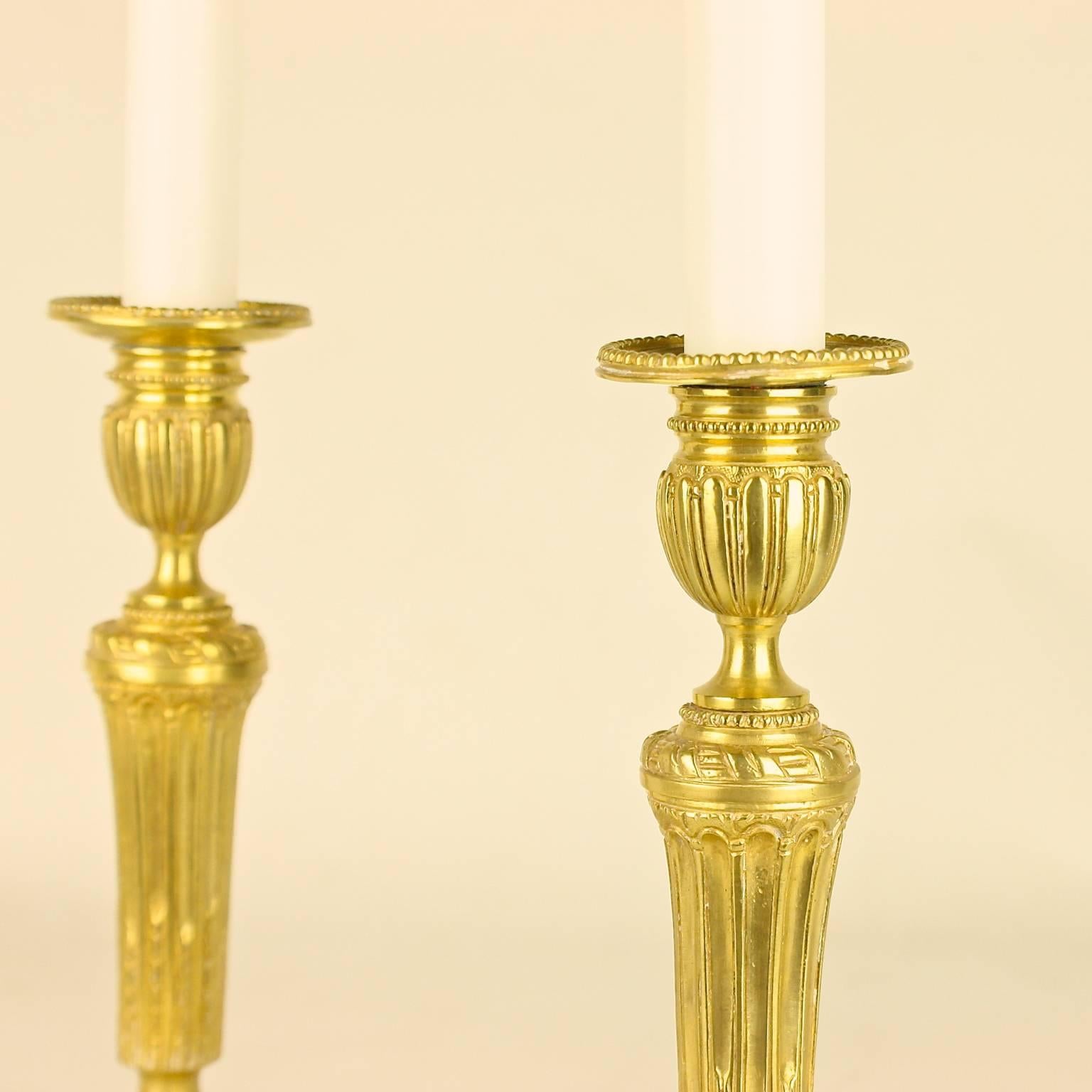 Pair of finely cast candlesticks, each with a tapering fluted stem surmounted by a ribbon tied garland, the gadrooned candle nozzles corresponding to the gadrooned circular doomed bases.
Candlesticks were in frequent use and thus required regular
