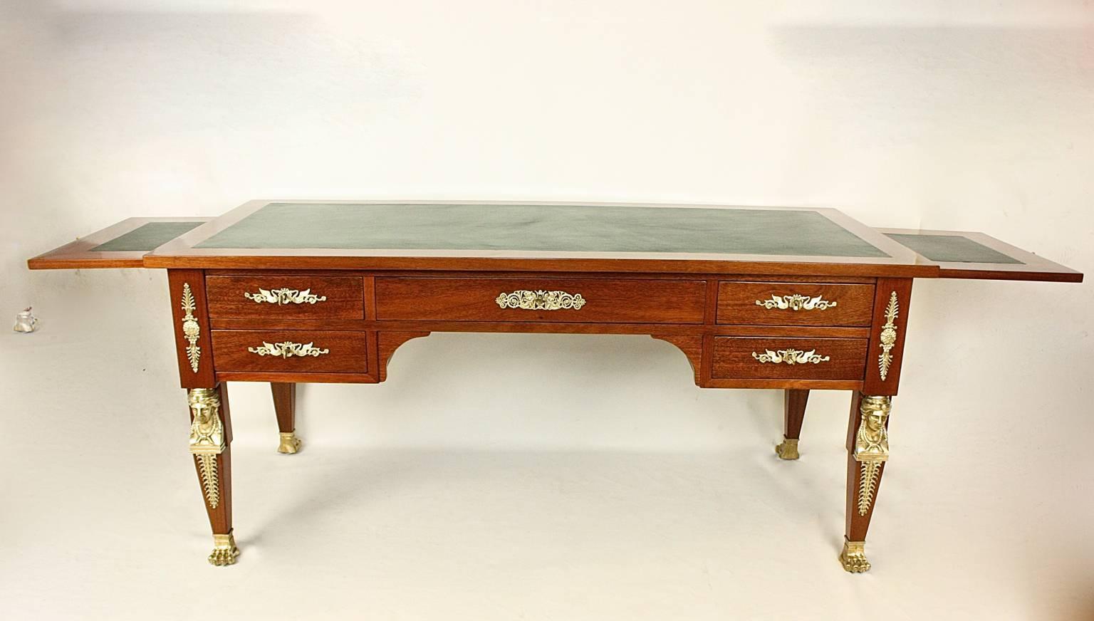 A large Empire gilt bronze-mounted writing table or bureau plat veneered in mahogany on a carcase of oak, the top inset with a green leather writing surface above a central long drawer flanked to each side by two short drawers. On the back of the
