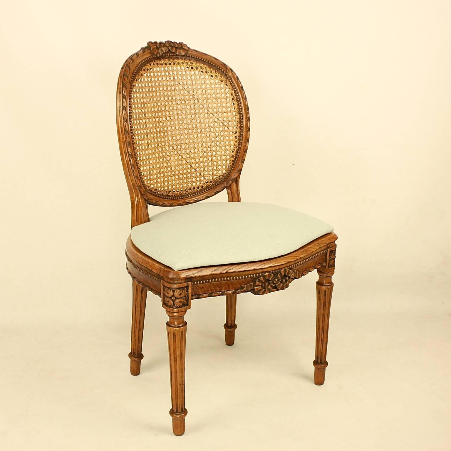 A set of six Louis XVI dining chairs in the manner of Georges Jacob (1739-1814). Each with a curved oval-shaped caned back, the carved cresting centered by a ribbon tied bow, the serpentine-fronted seat rail repeating the bow design in its center,