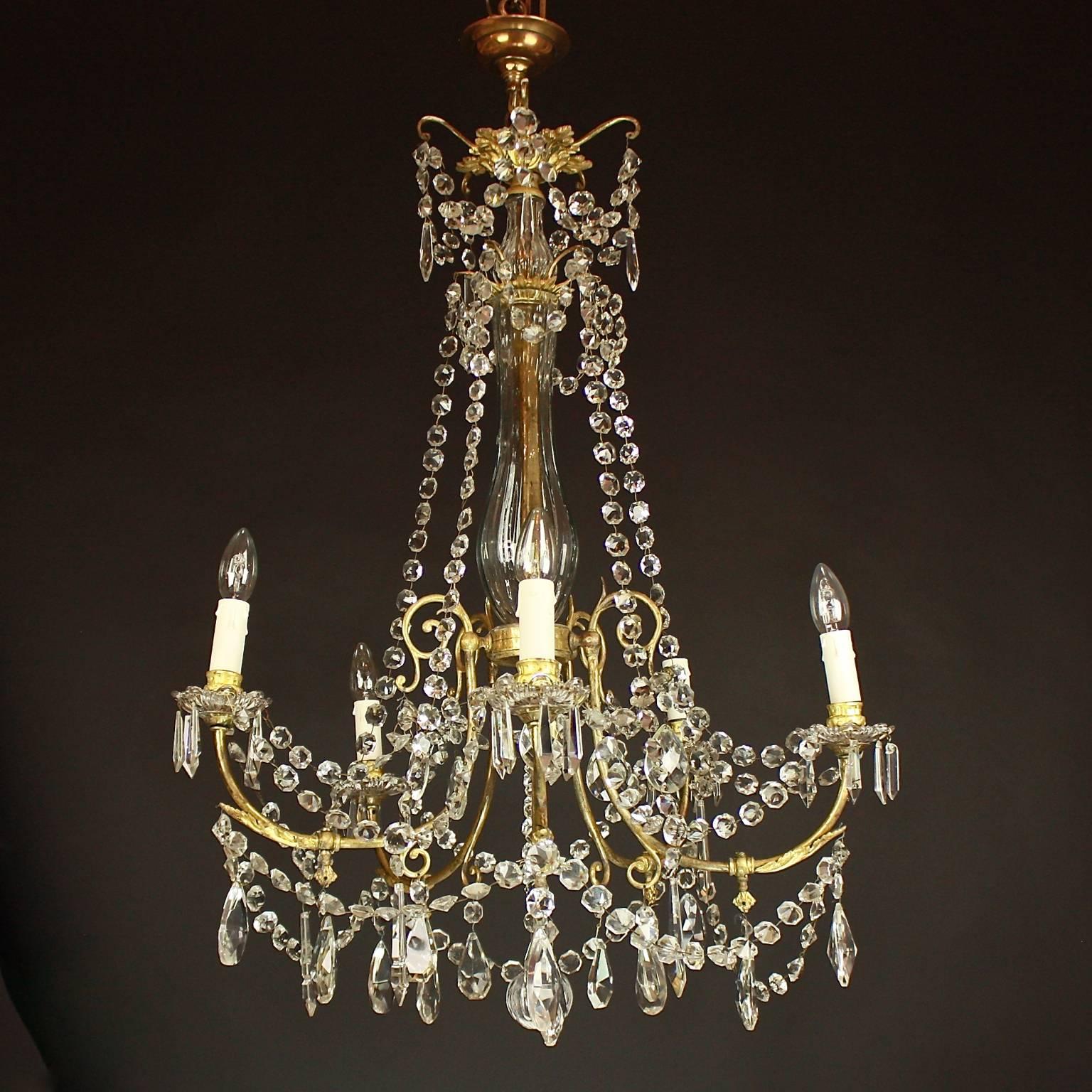 A 19th century Louis XV style gilt bronze and cut-crystal chandelier, with a facetted multi-baluster stem, a vase-d'enfilade, the nozzles and drip pans on scrolled branches with supporting foliate, with suspension cut-crystal chains to the corona.