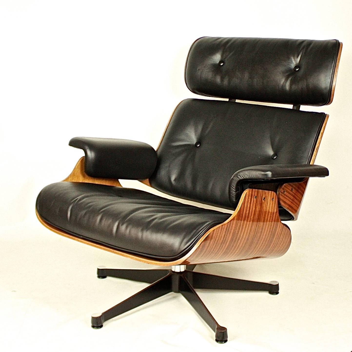 Pair of Ray and Charles Eames Style lounge chairs and one ottoman, after the famous mode designed 1955 by the Eamses and manufactured by Herman Miller. The rounded rectangular back and seat moulded in three sections and upholstered in black hide, on