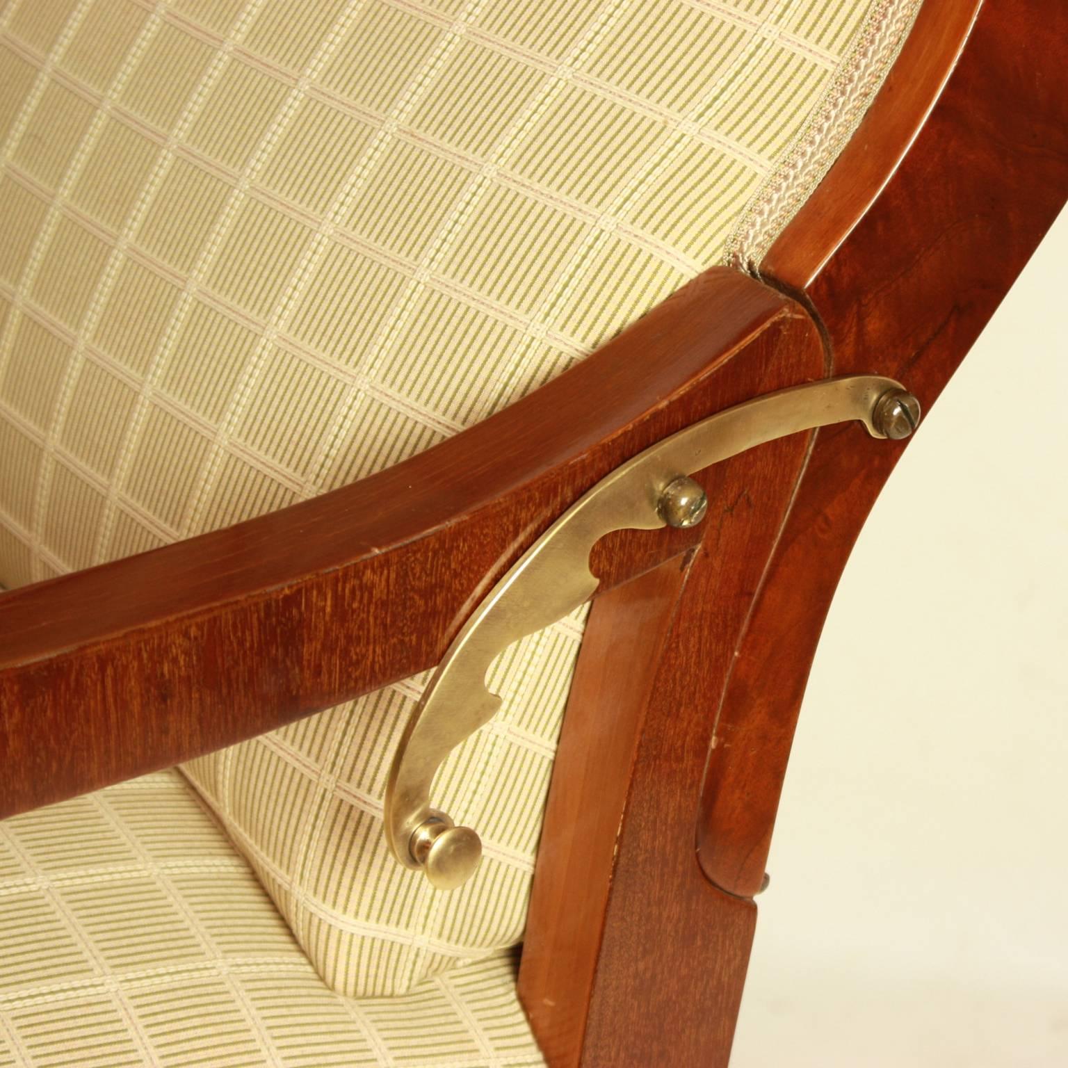 A large, impressive Biedermeier wing chair with adjustable declining back. Made of cherrywood, with its warm hue very fitting to the grey beige cotton fabric with its fine latticework pattern.
A wing chair with a rectangular back, the arm ends