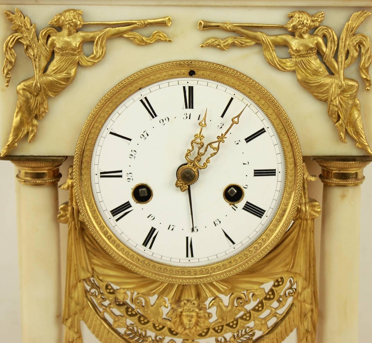 A French Empire alabaster portico clock with finely chased ormolu mounts. The white enamel dial with Roman numerals and pierced gilt hands, contained within a delicately chased and pierced drapery (presenting the central bust of Appollon) framed