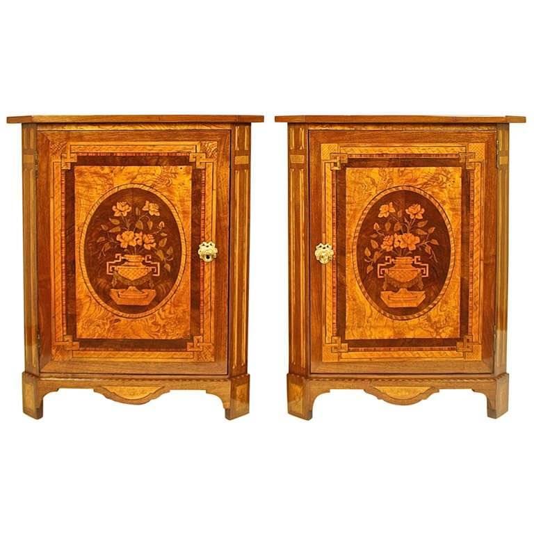 An exceptional pair of corner cabinets or encoignures each with a marquetry top above canted corners simulating fluting, the panelled door with flowers in a vase made of precious woods i.e. burl ash, walnut, fruit woods, with pyrogravure and