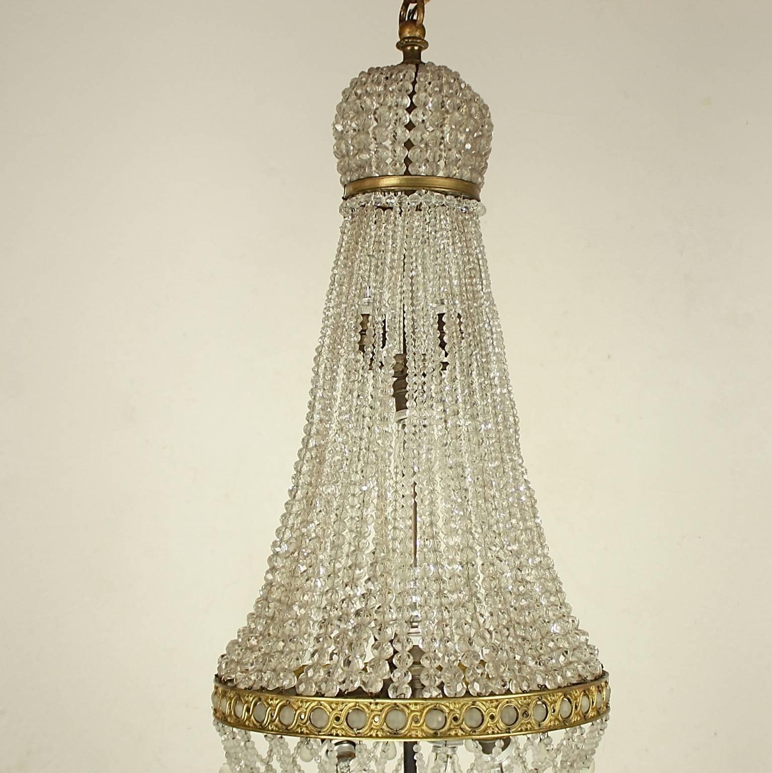 Un raffinato lampadario a tenda e a sacchetto in bronzo dorato con una corona a forma di corona fatta di piccole perle sfaccettate sopra una sottile fascia di bronzo, da cui pendono catene di perle graduate in cristallo tagliato fino a un'elaborata