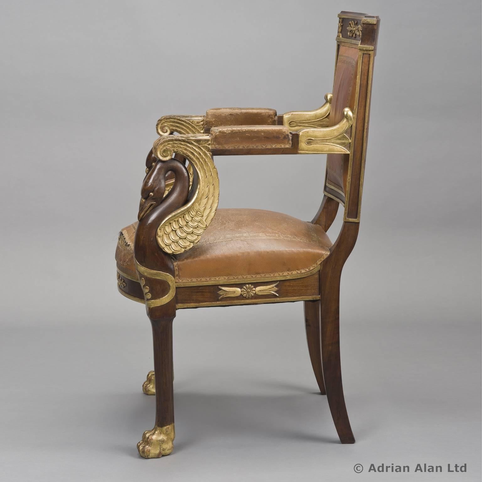 An Empire style mahogany parcel-gilt fauteuil.

The rectangular back with a rosette, foliate and anthemion carved top rail, lotus and foliate scrolled arms with swan neck supports and a bowed seat, upholstered throughout in gilt-tooled tan
