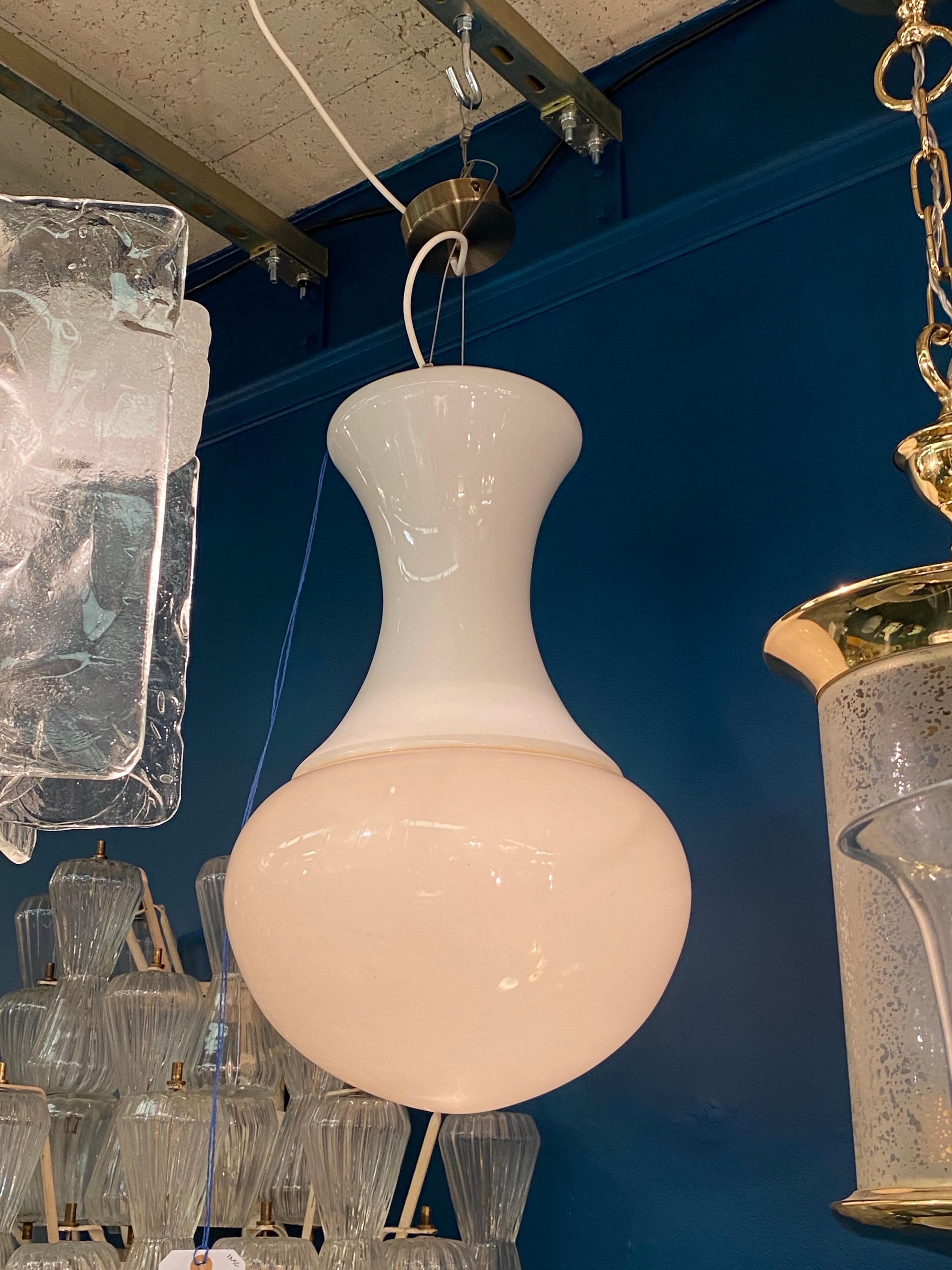 Una lampada a sospensione italiana dal design pulito ed elegante, circa 1970. Il ciondolo è composto da due pezzi di vetro soffiato a mano realizzato a Murano. La parte superiore è in vetro bianco opaco e la parte inferiore in vetro opaco color