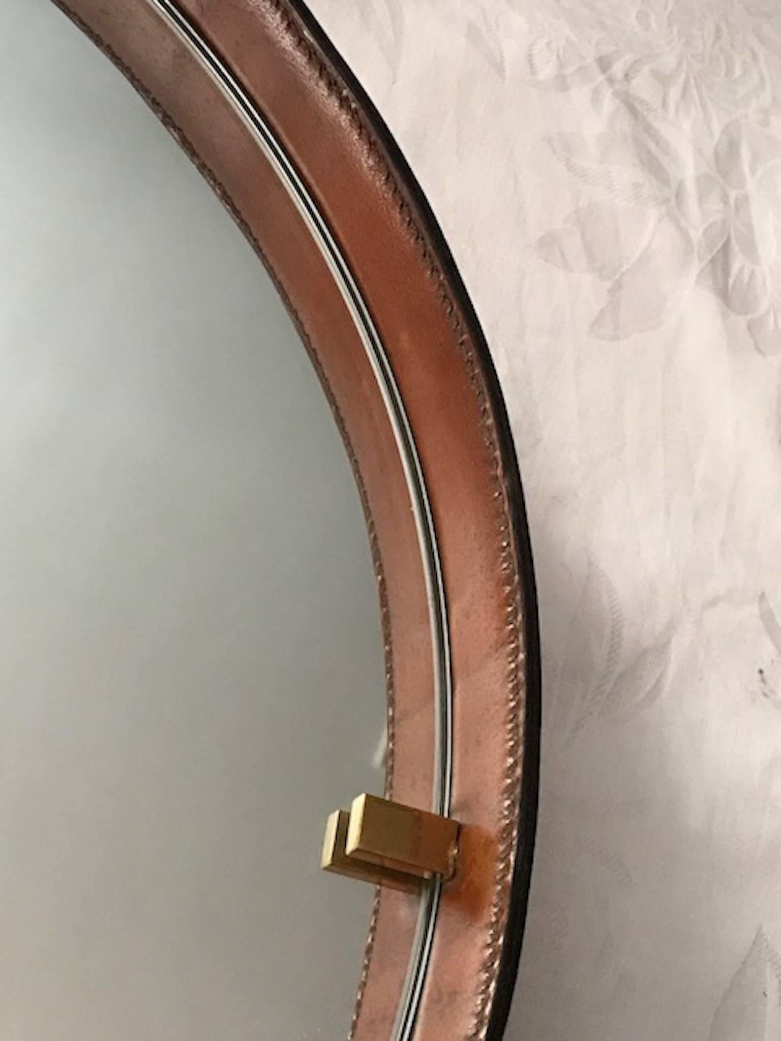 A great post war 1940s-early 1950s Italian round leather mirror suspended from a thick cotton braid cord. The mirror has stitched seams on the outer edge of the leather and it is perfectly distressed from age. Original patina on brass and original