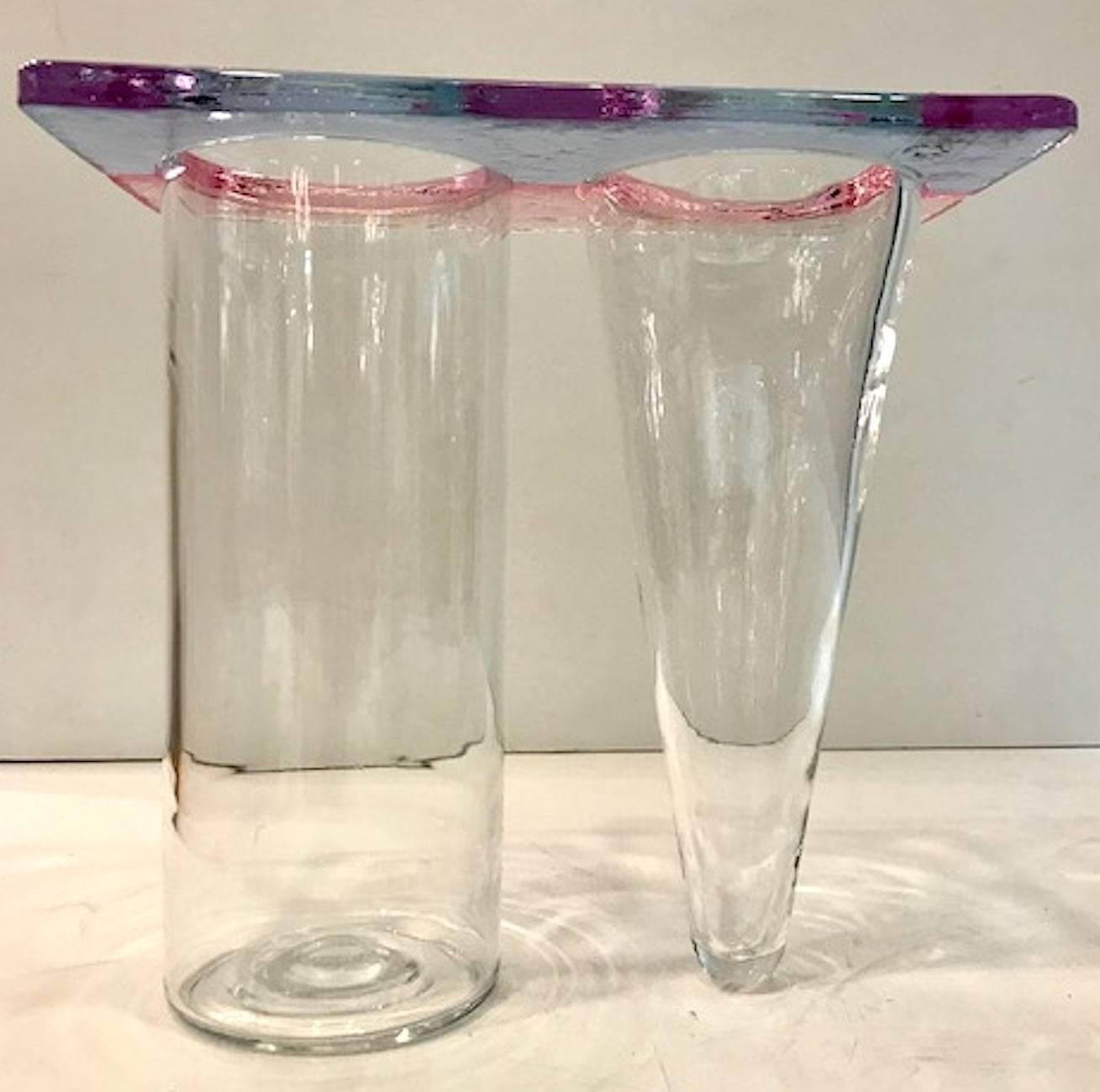 Eine Doppelvase mit geometrischem Design, typisch für den Memphis-Stil der 1980er Jahre. Die Doppelvase aus hellblauem, rosafarbenem und klarem Glas ist auf der einen Seite säulenförmig und auf der anderen Seite kegelförmig geblasen. Sehr sehr guter