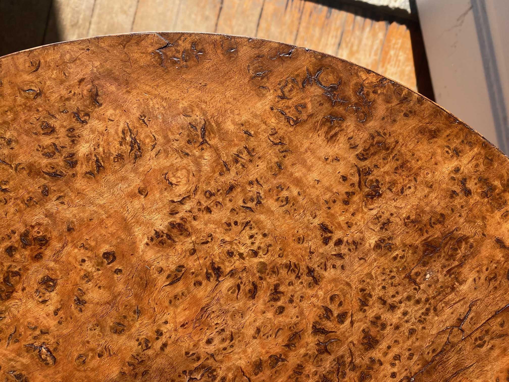 Une table tripode de campagne avec beaucoup de caractère et de charme. Le plateau est plaqué en deux pièces de ronce de chêne magnifiquement figurée. Le plateau est soutenu par une tige tournée de manière élaborée qui repose sur trois pieds en forme