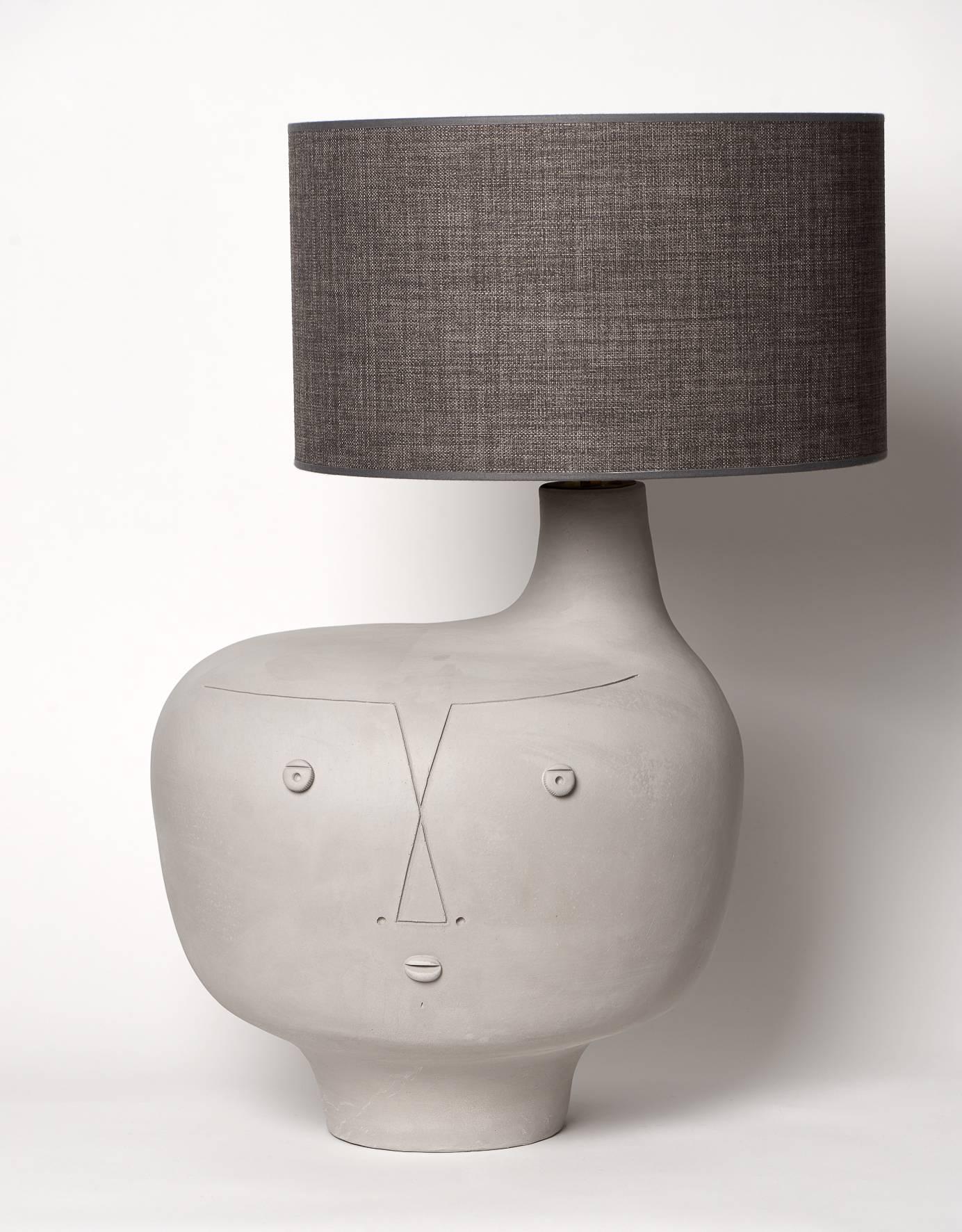 Important Biomorphic gray earthenware base lamp, not glazed, with raw aspect, decorated on the front with a stylized visage incised, creation 2016.

All the Dalo's creations are unique pieces (sculpted and never molded) and signed by the French