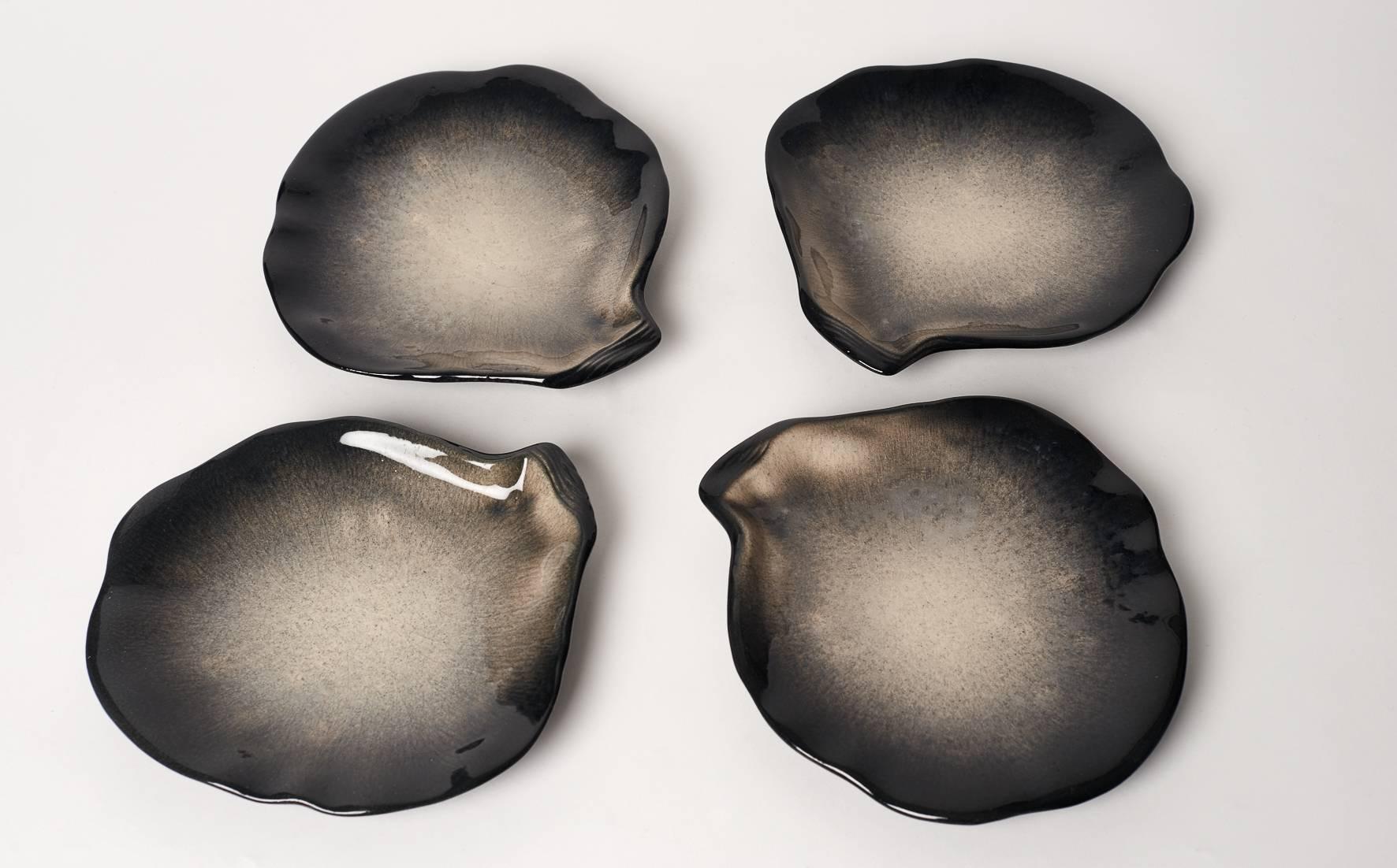 Pol Chambost (1906-1983), France.

Four black and grey plates looking like pearly sea shell.
 Signed Pol Chambost, France.