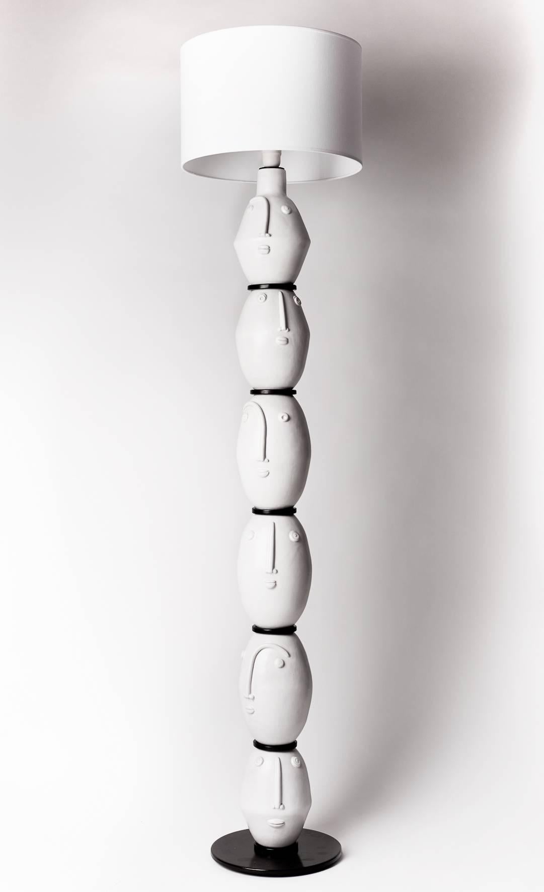 White enameled ceramic pieces with stilized faces, black patined steel base and circles for this floor lamp.

 Unique piece by French ceramists DaLo.

 Height dimensions approximate are without the electrical socket system on top, and without the