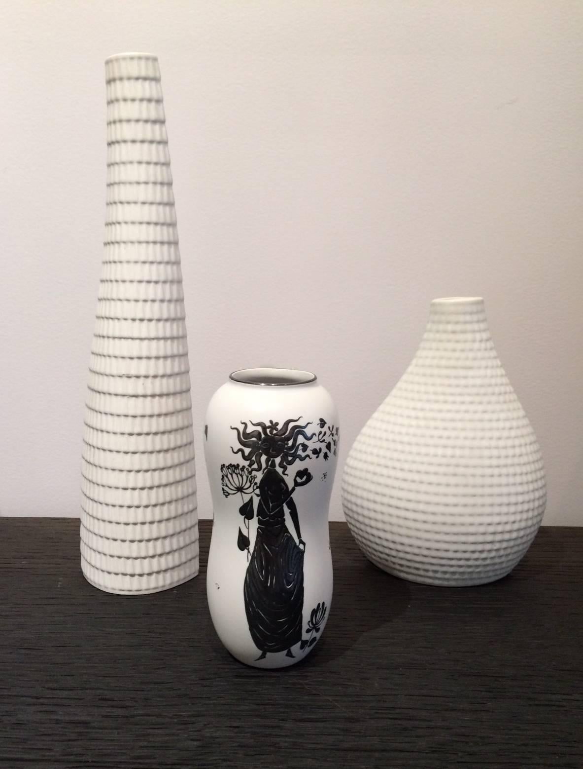 Stig Lindberg (1916-1982).

Two vases "Reptile" white ceramic (1970s).
Measures: H 31 cm (signed) and 18 cm (not signed).

One vase "Grazia" white with black enameled woman and leaves (1960s).
Measures: H 15 cm