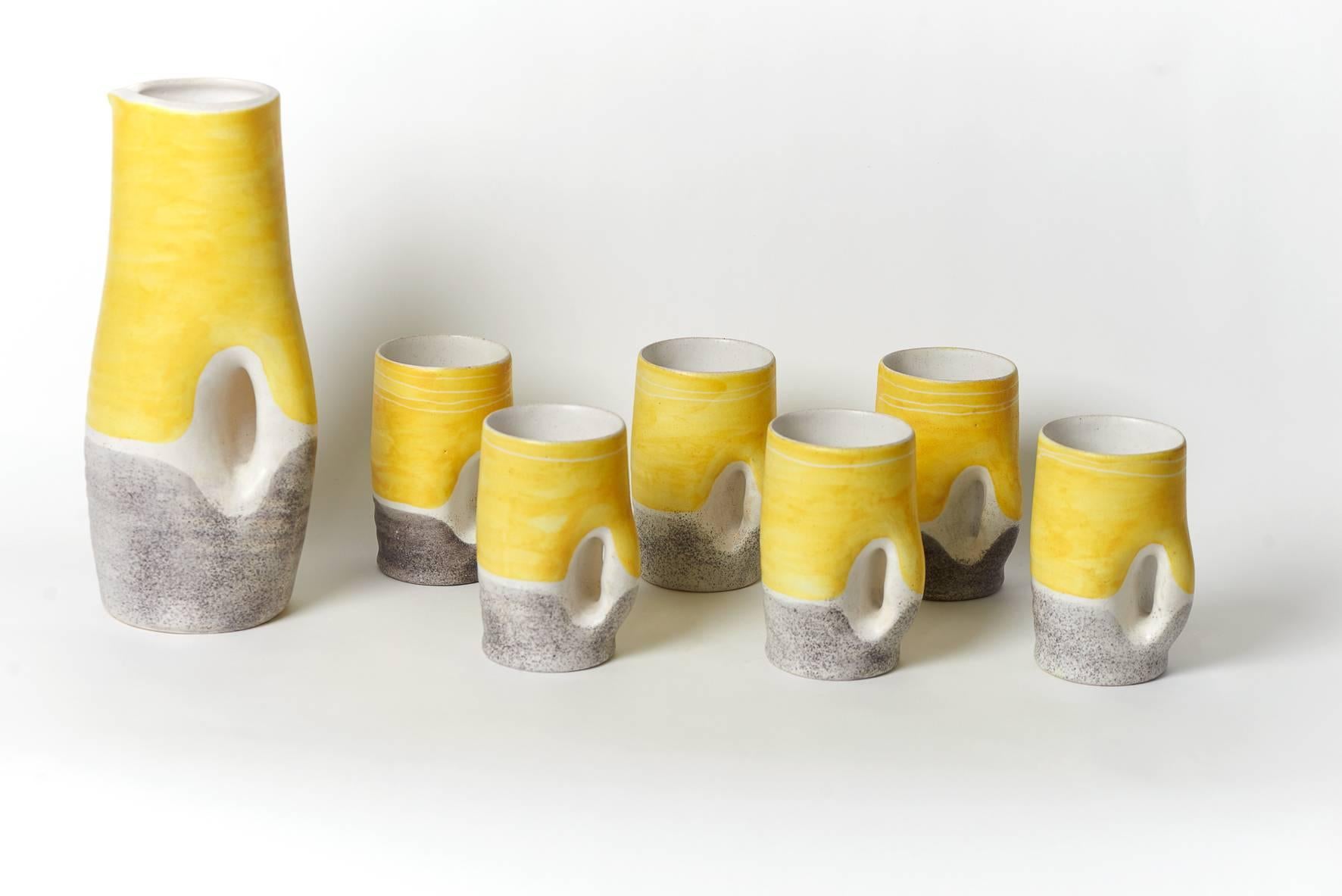 Yellow and grey glazed stoneware soft drink set by French ceramist Mado Jolain
Pitcher Signed MJ
1950s

Dimensions 
Pitcher H 33 cm X L 15 cm
Glass H 15 cm X L 10 cm (X 6).