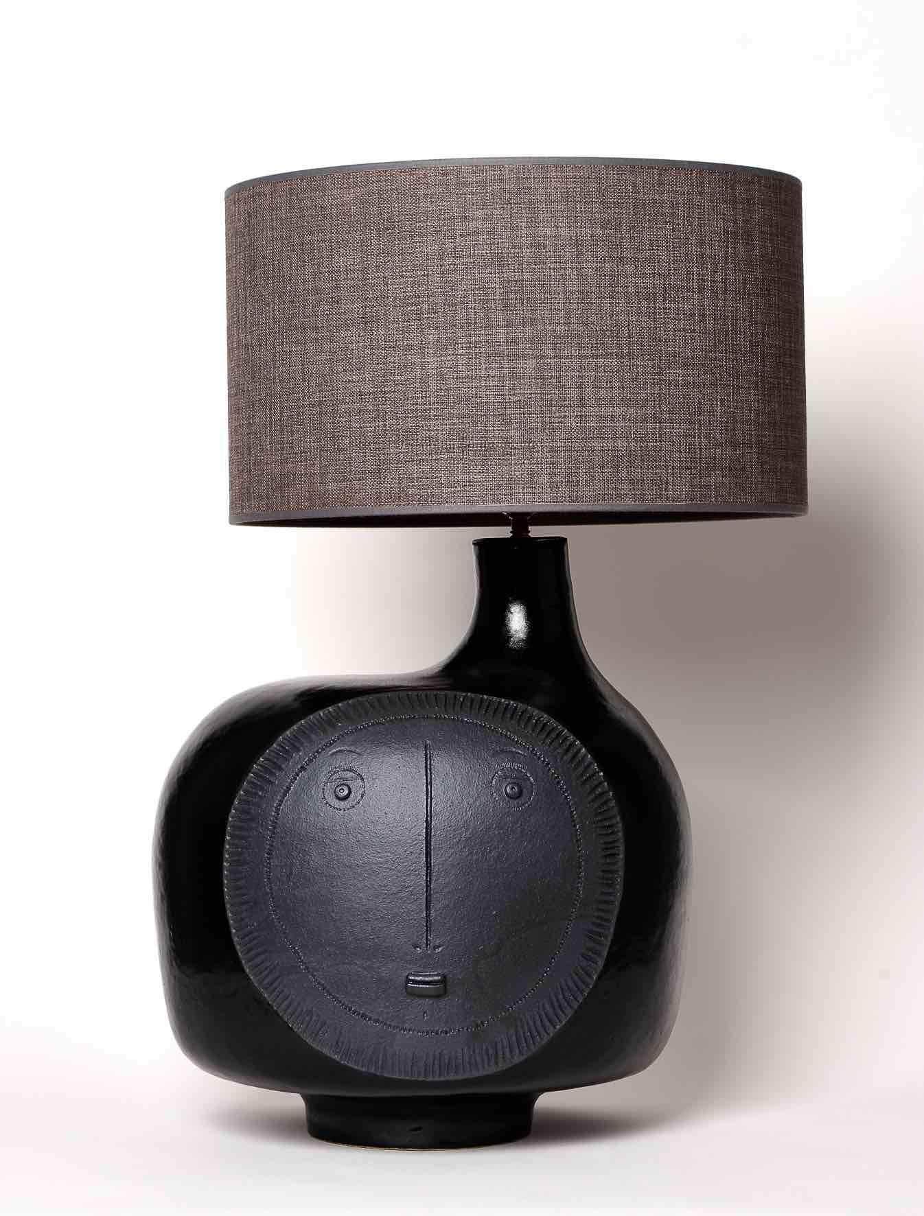 Handmade biomorphic sculpture forming lamp-base, stoneware glazed in deep shiny black and decorated with a stylized mat medallion visage.

One of a kind piece signed by the French ceramicists Dalo.

The height dimensions are for the pottery