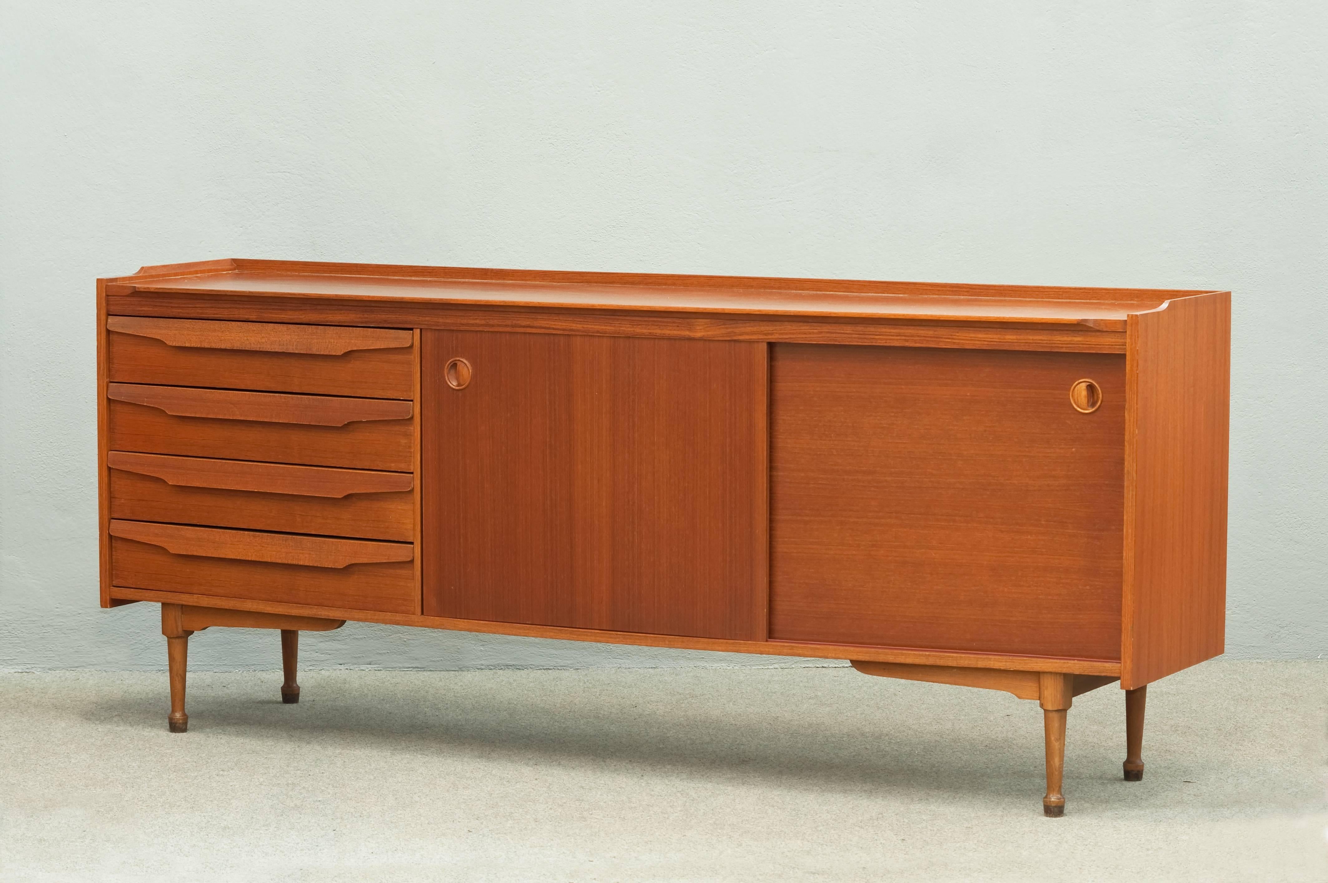 Teak sideboard with two sliding doors and four drawers.