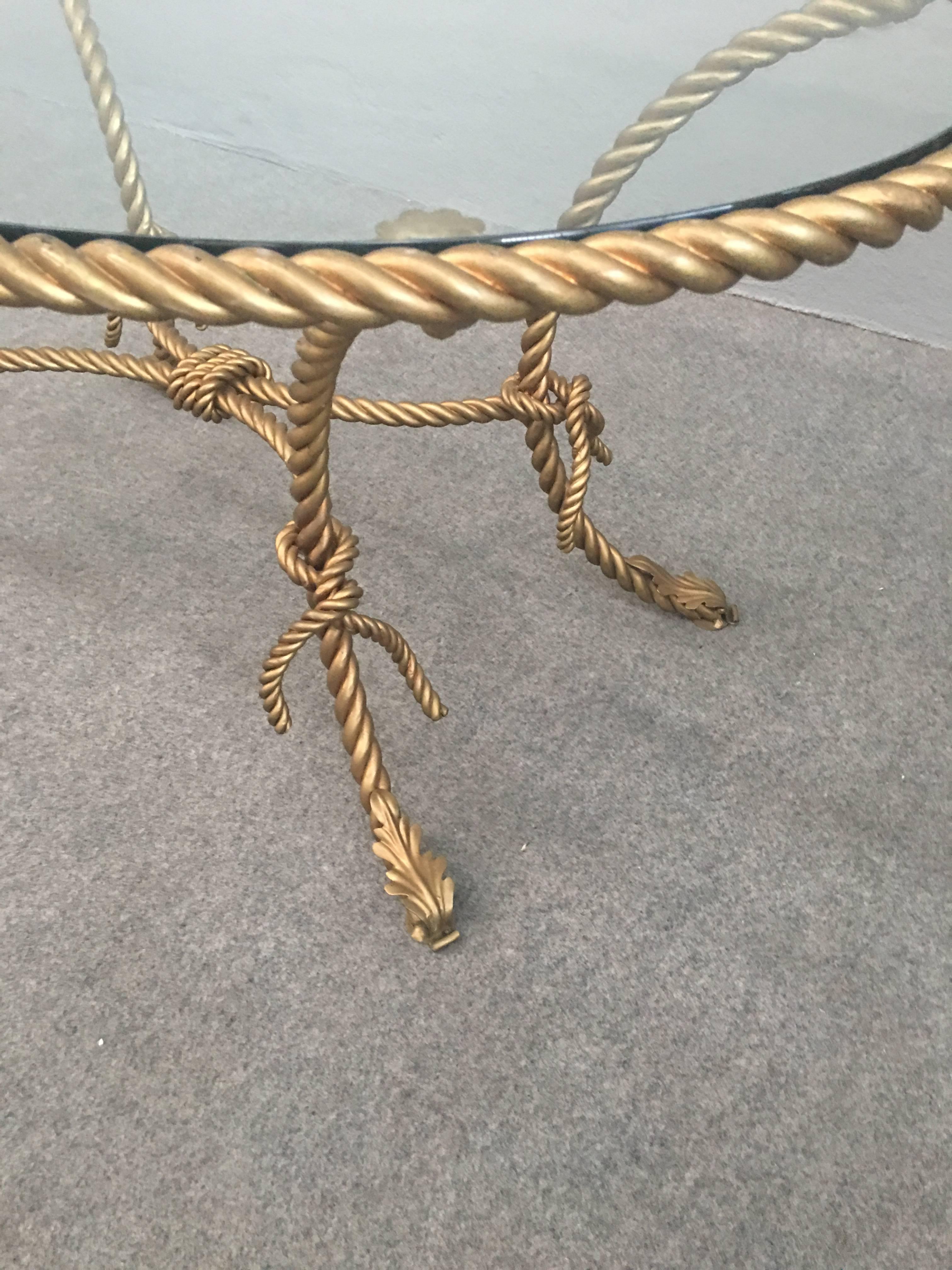 Very elegant and glamorous oval coffee table.
Gilded iron twist with bows base and original glass top.