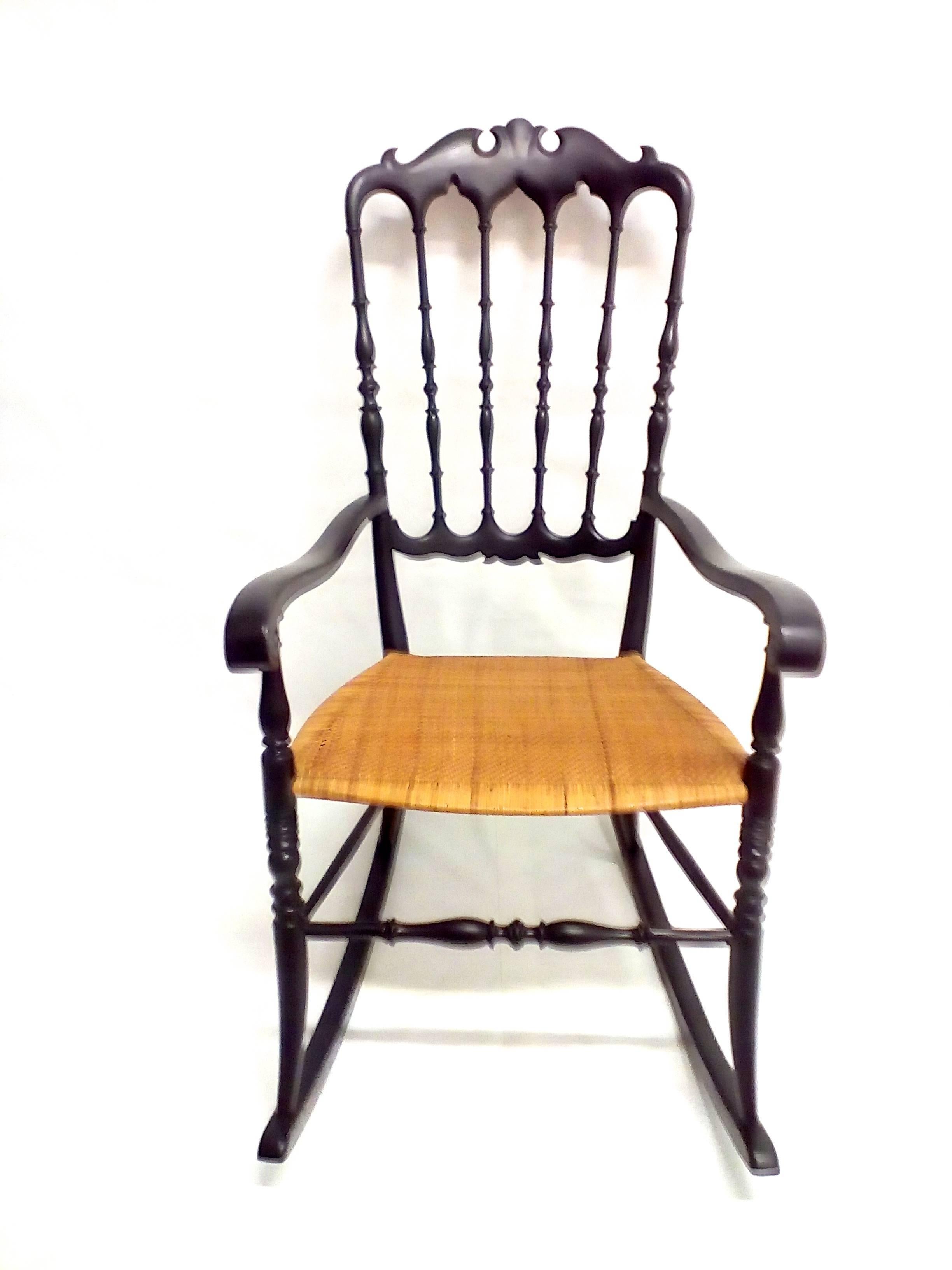 Articulate rocking chair. Black wood and wicker seat with elegant design.