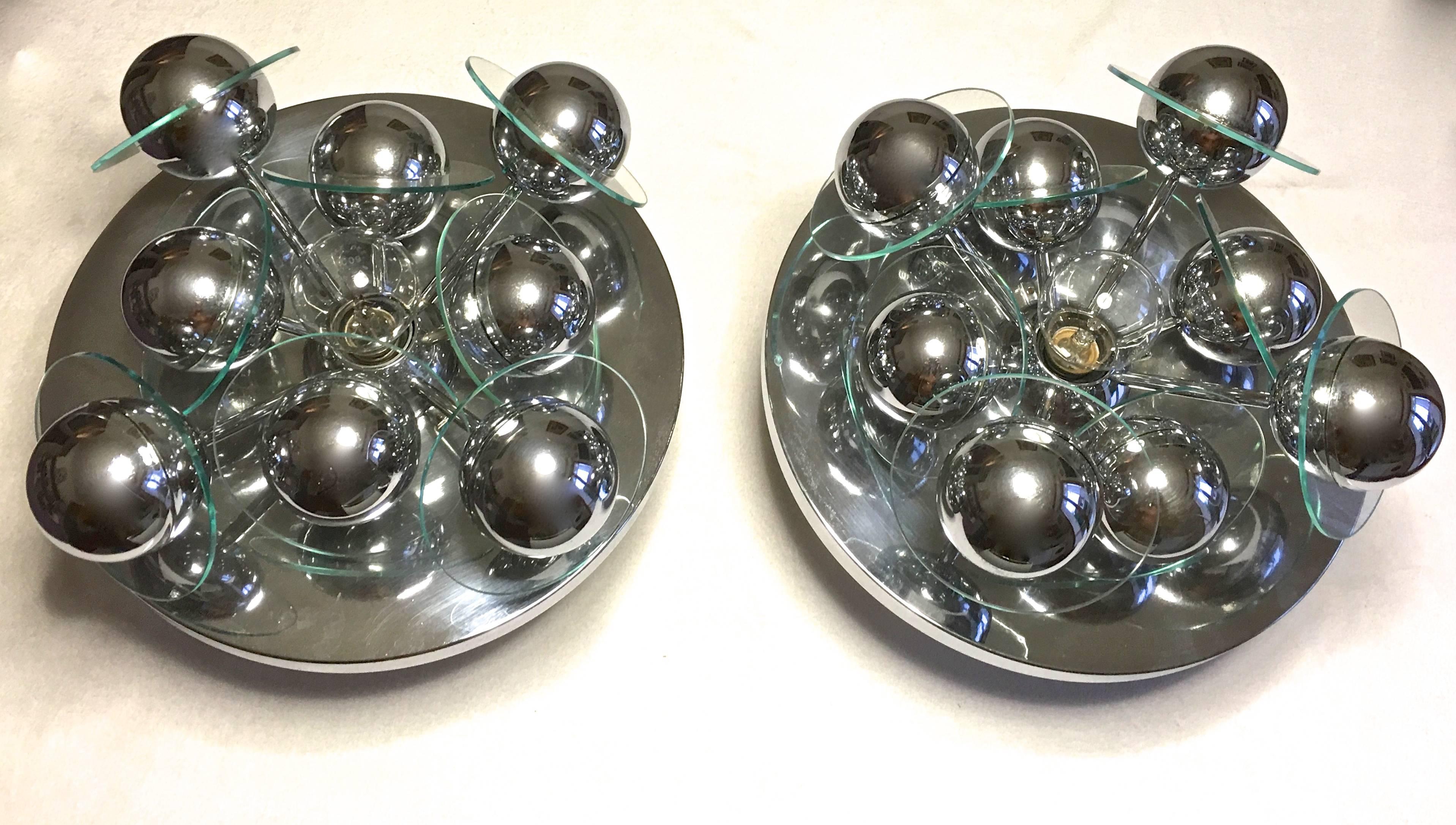 These two Mid-Century Sputnik lights mounted on a chrome base hold eight silver coloured spheres with glass discs. In the center a single big bulb spreads the light beautifully reflected by the spheres and the glass rings.